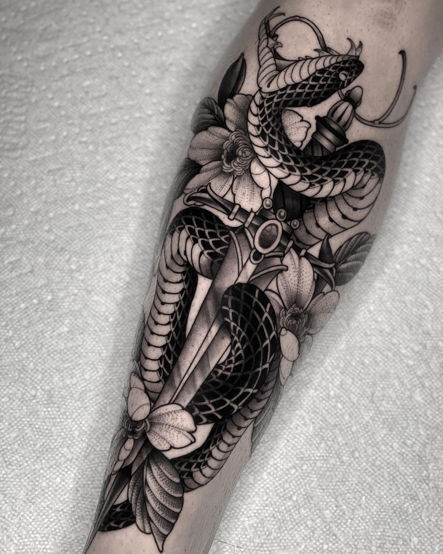 Snake and flowers dotwork tattoo on the forearm by San Diego