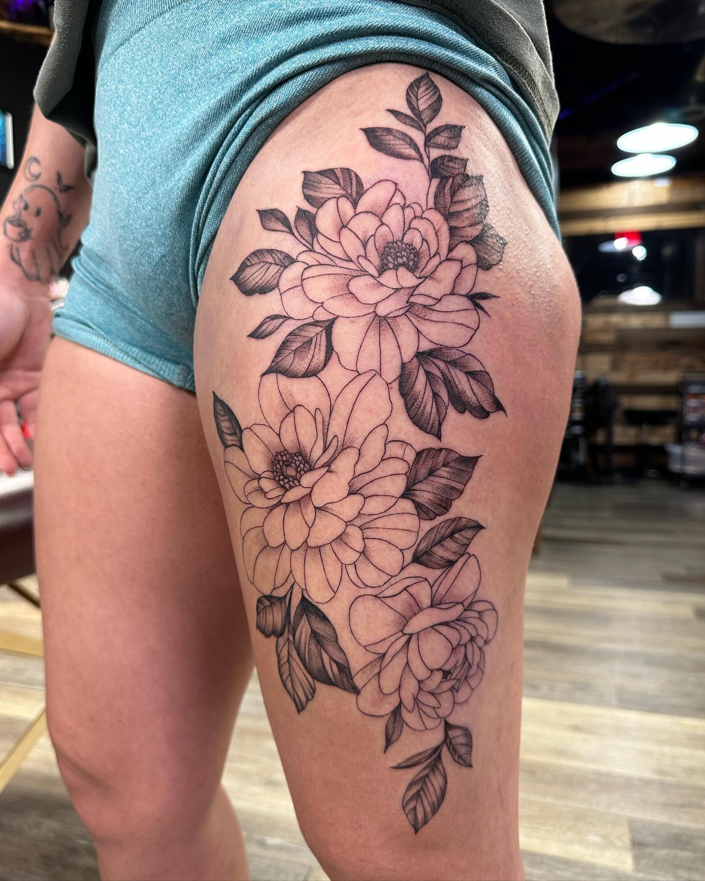 Floral bouquet black and grey tattoo on the thigh by Emmy