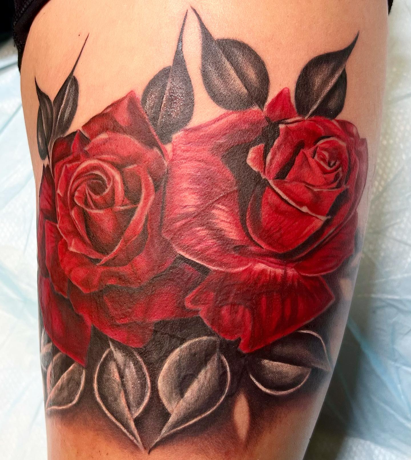Red roses realism tattoo on the thigh by The Tattoo Saint- DMV Tattoo Artist, Hyattsville, Maryland