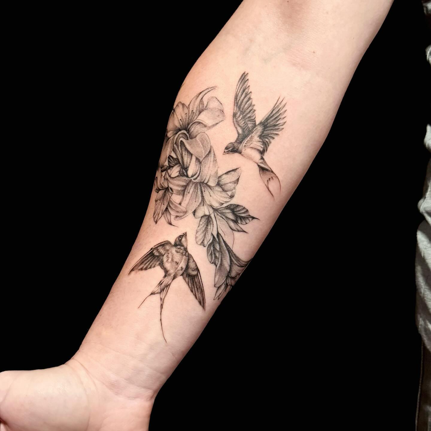Birds and flowers black and grey tattoo on the forearm by Navei