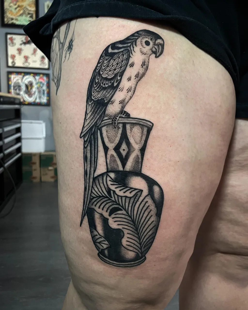 Parrot and vase black and grey tattoo on the thigh by Lauren Vandevier
