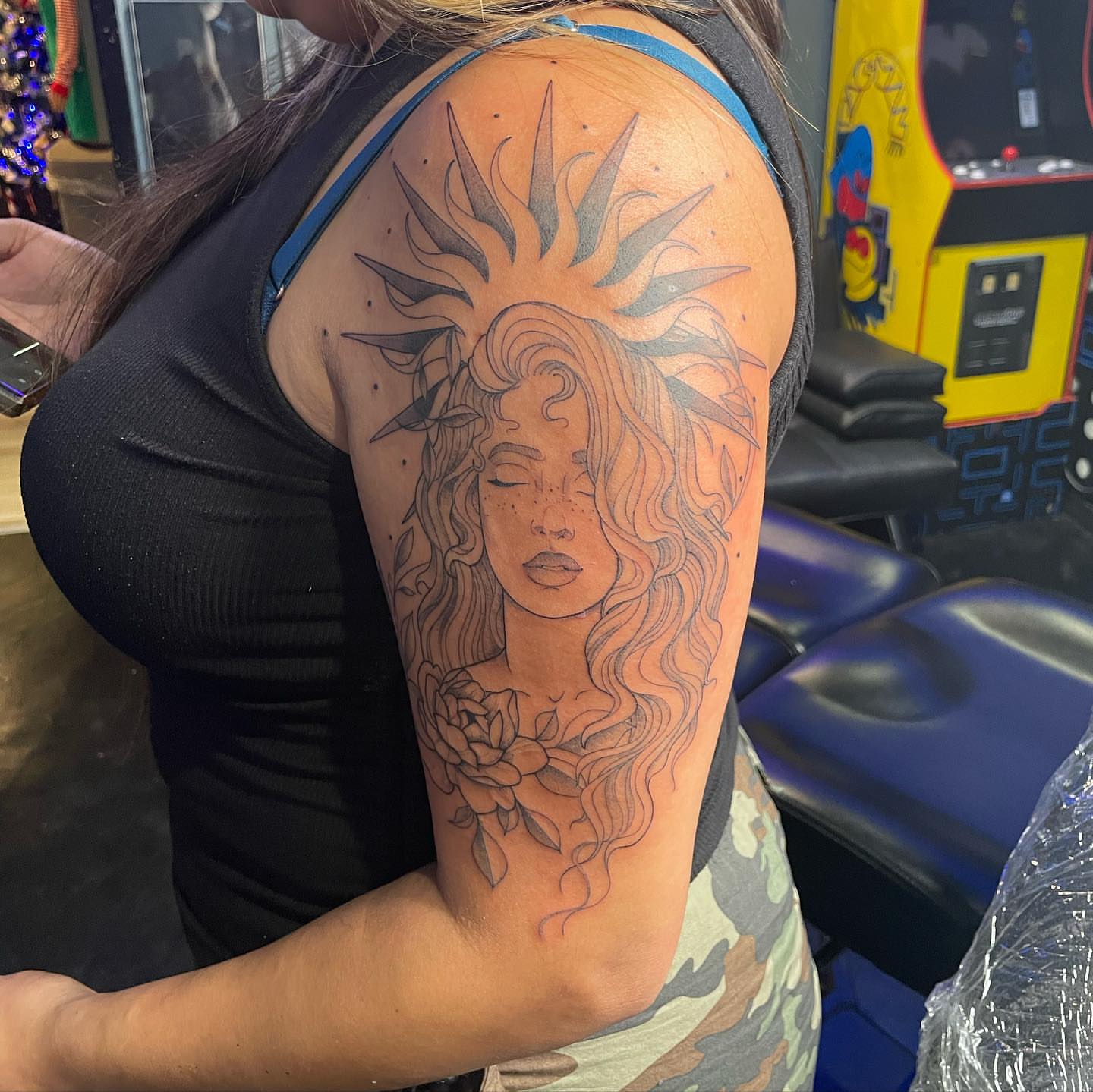 Woman with sun dotwork tattoo on the upper arm by Abel Ponce