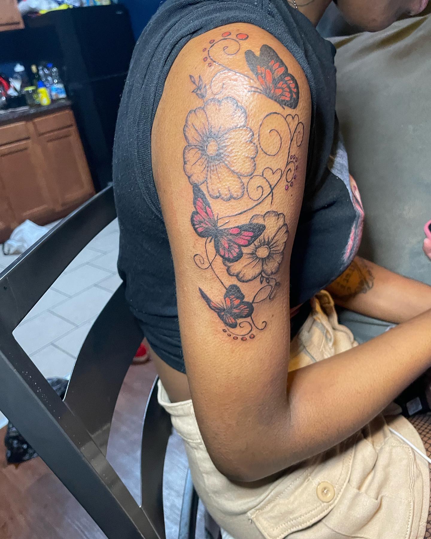 Flowers and butterflies dotwork tattoo on the upper arm by Dinero Inks