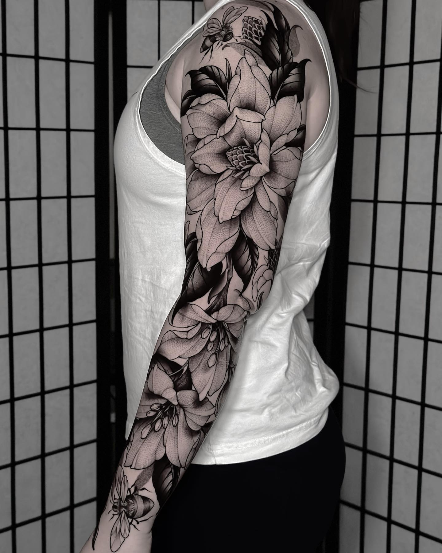 Flower and bee realism tattoo on the upper arm by San Diego