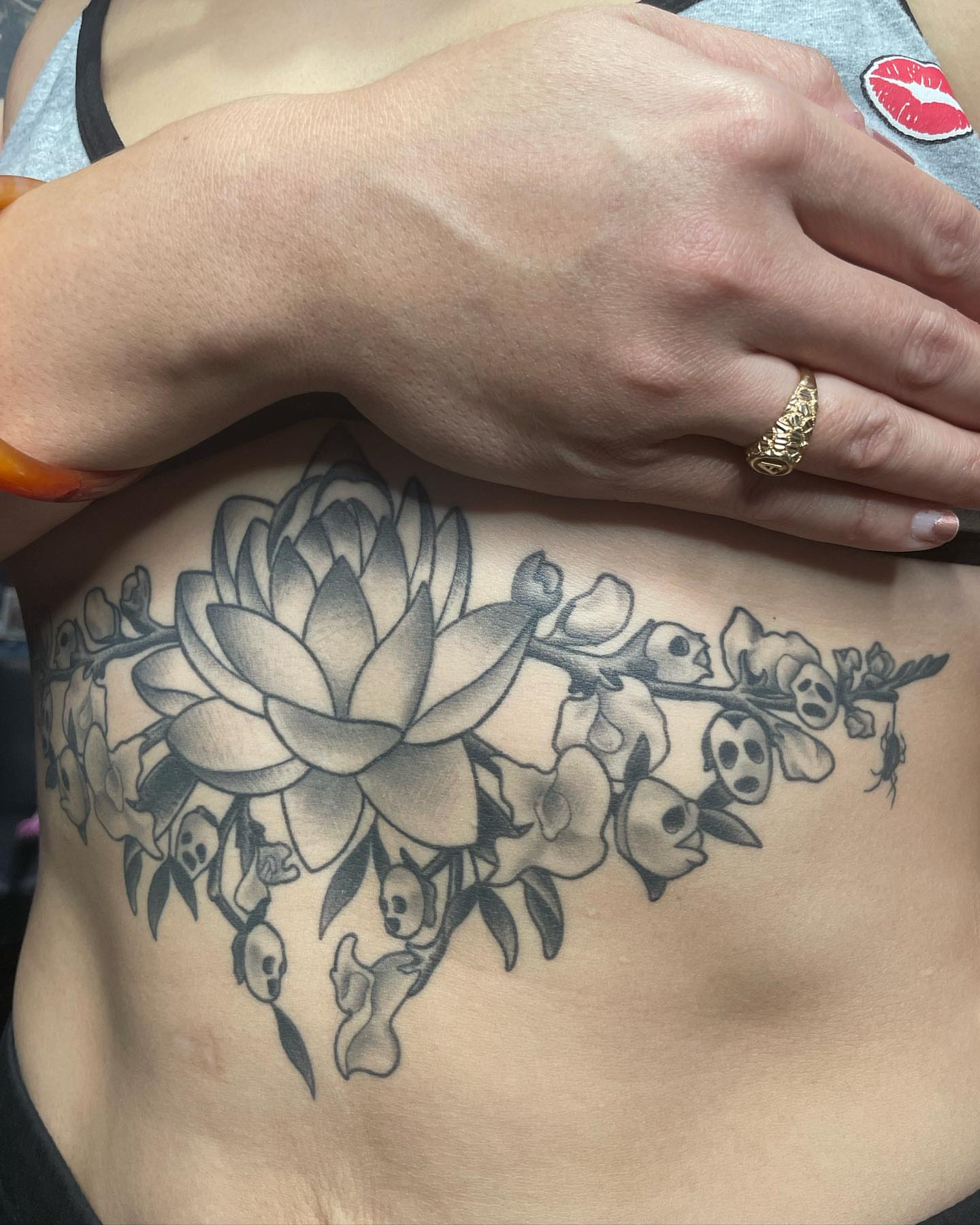 Lotus and skulls black and grey tattoo on the ribs by Abel Ponce