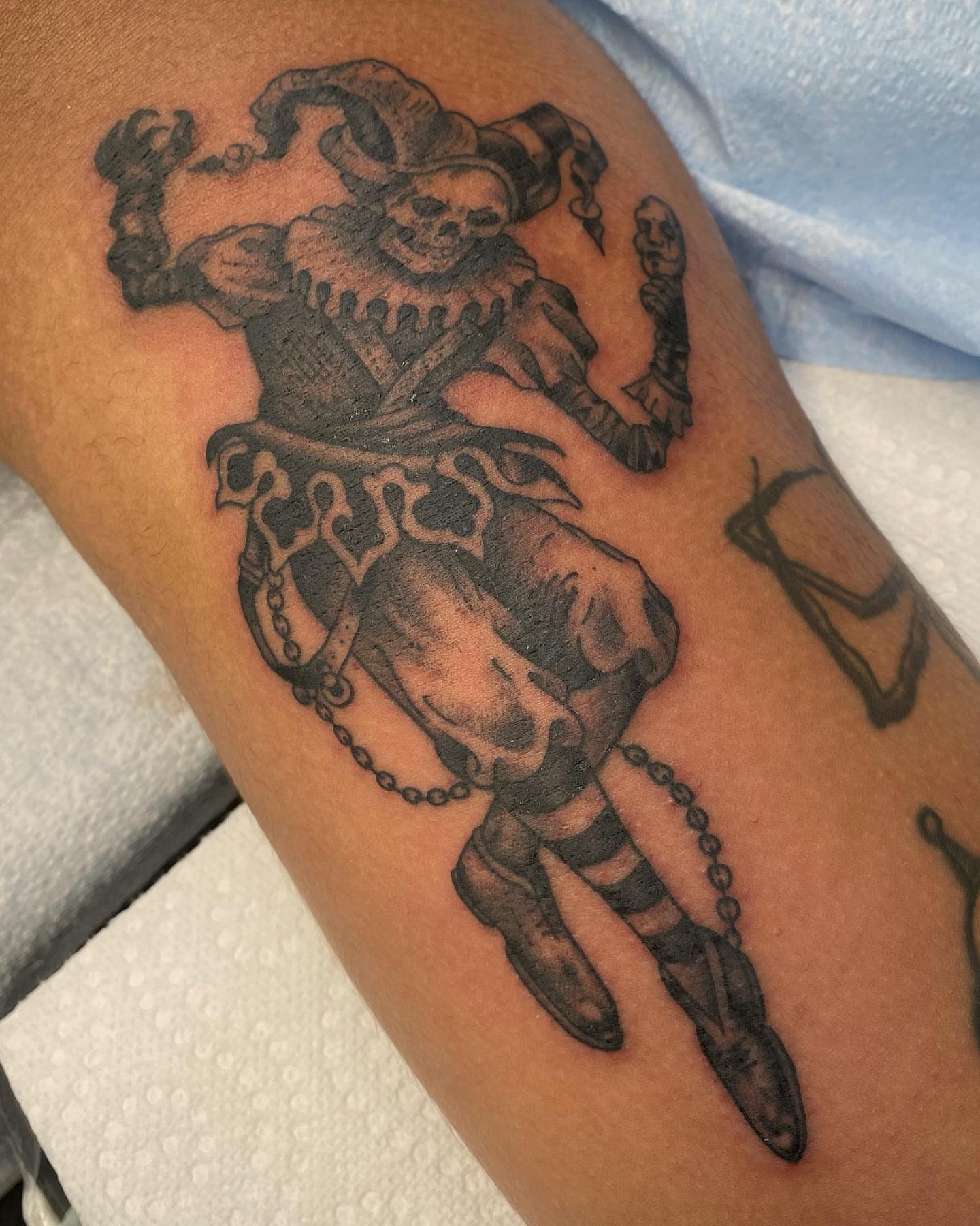 Jester black and grey tattoo on the thigh by Jesse Ortega