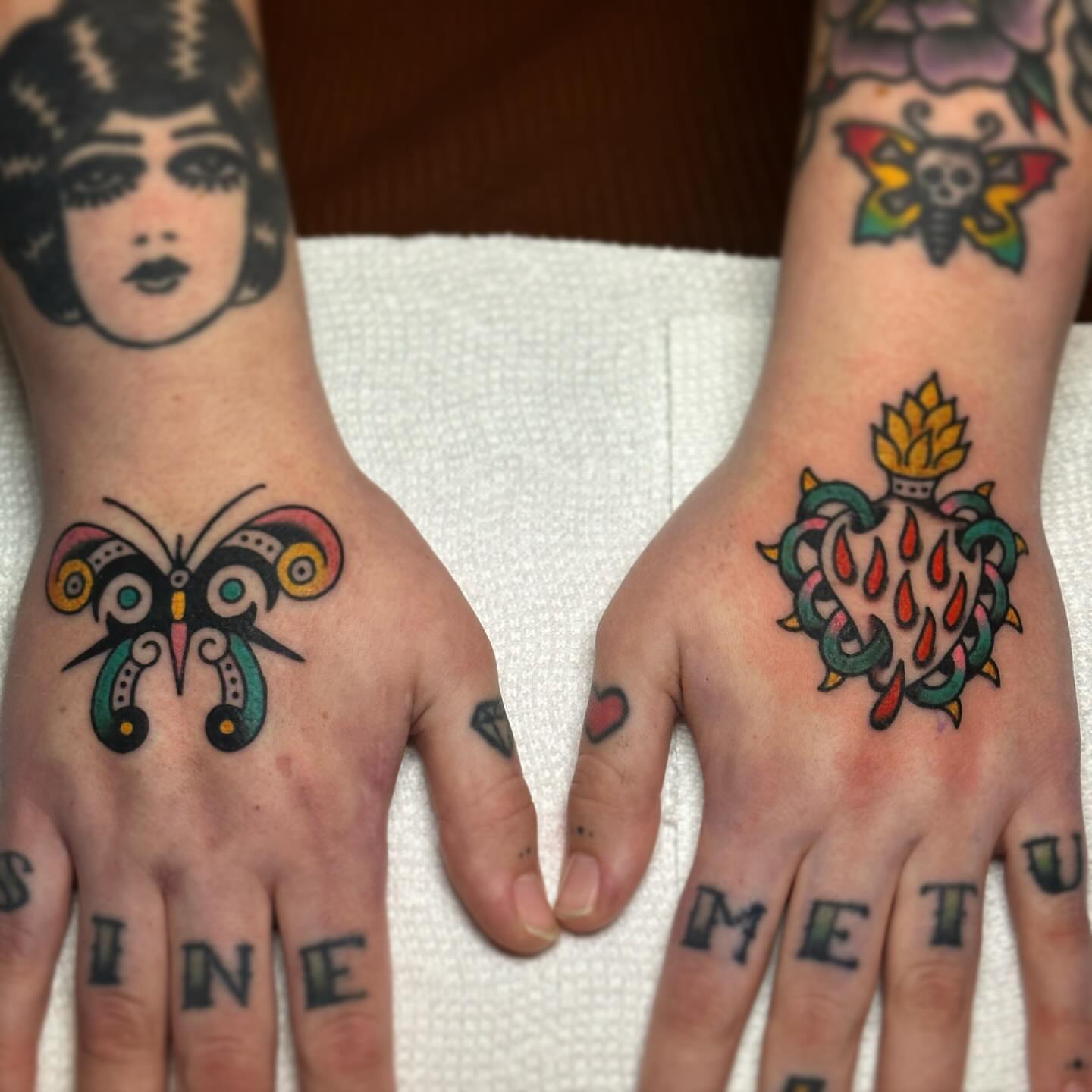 Butterfly and heart American traditional tattoo on the hand by Britney Goodman