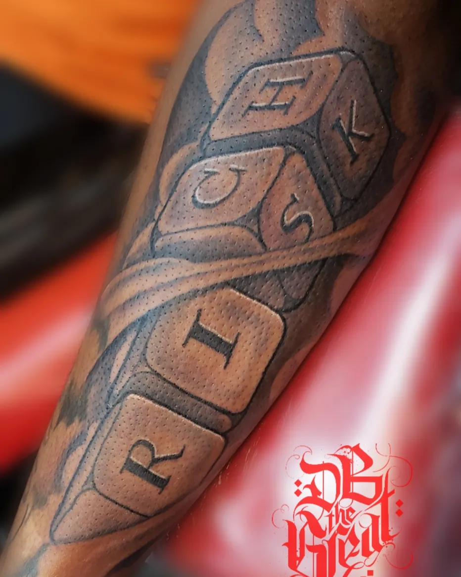 Dice black and grey tattoo on the forearm by Dannie Blythewood