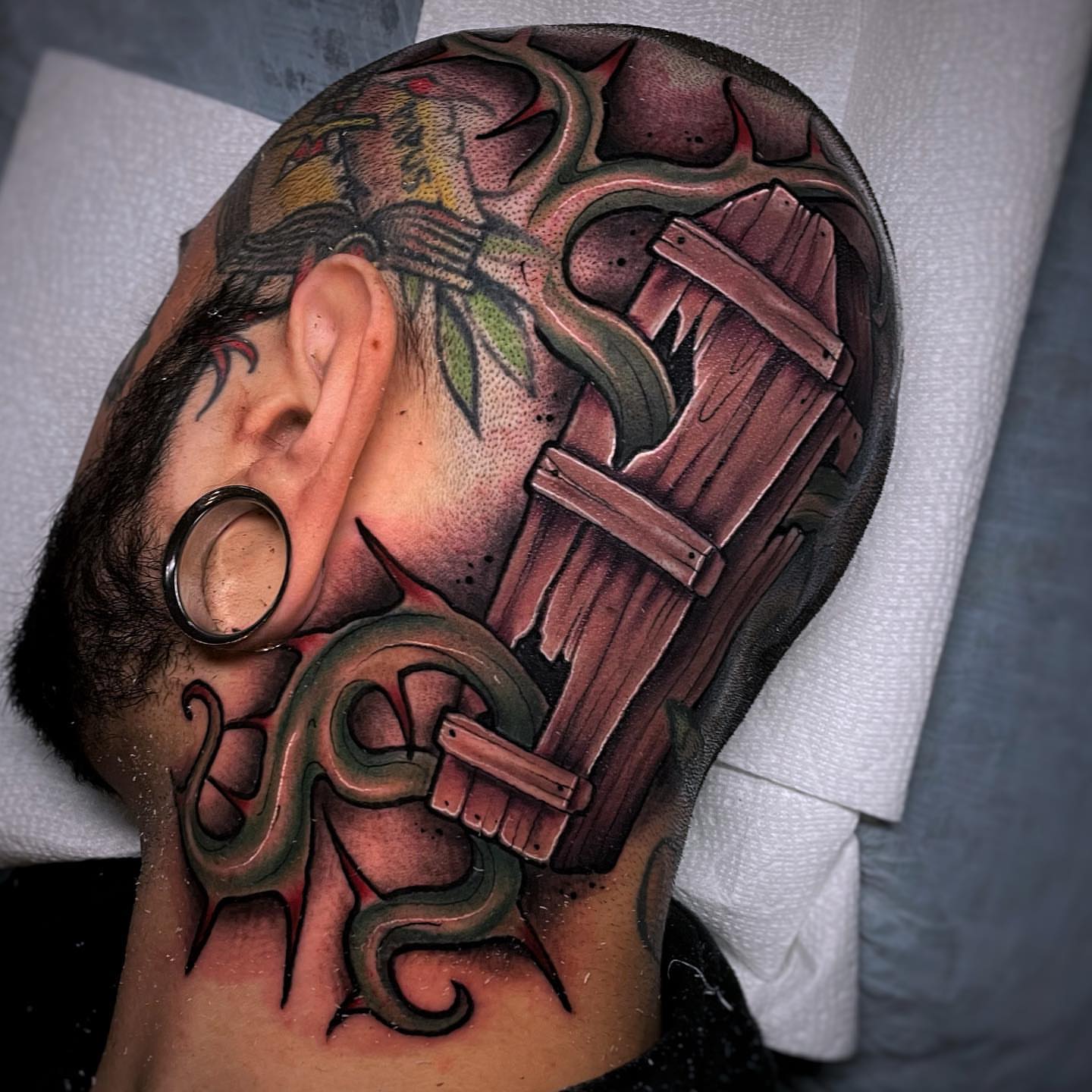 Wooden gate and snake realism tattoo on the head by Ick Abrams