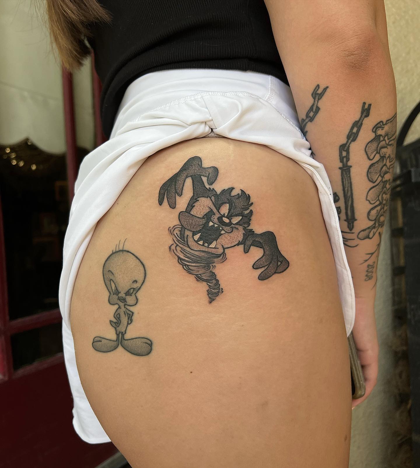 Tweety and Wile E. Coyote black and grey tattoo on the thigh by Daniel Patrick