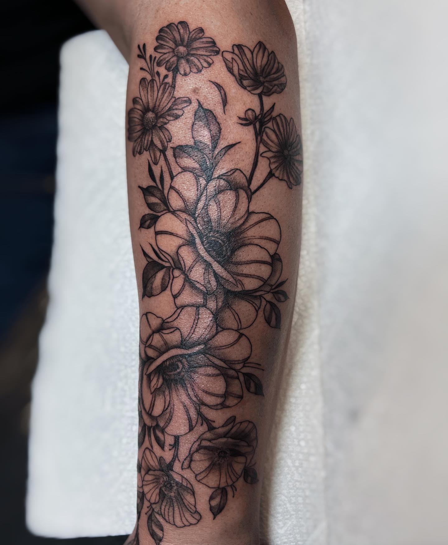 Floral arrangement black and grey tattoo on the forearm by Kolby