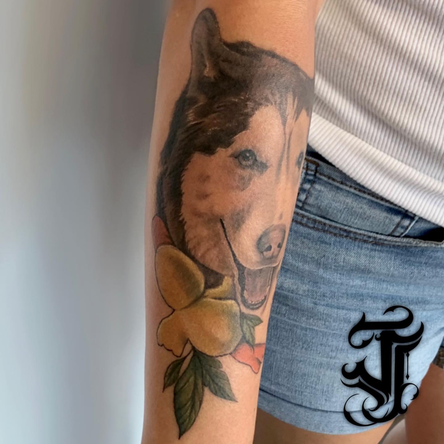 Dog with flower realism tattoo on the forearm by Justin James