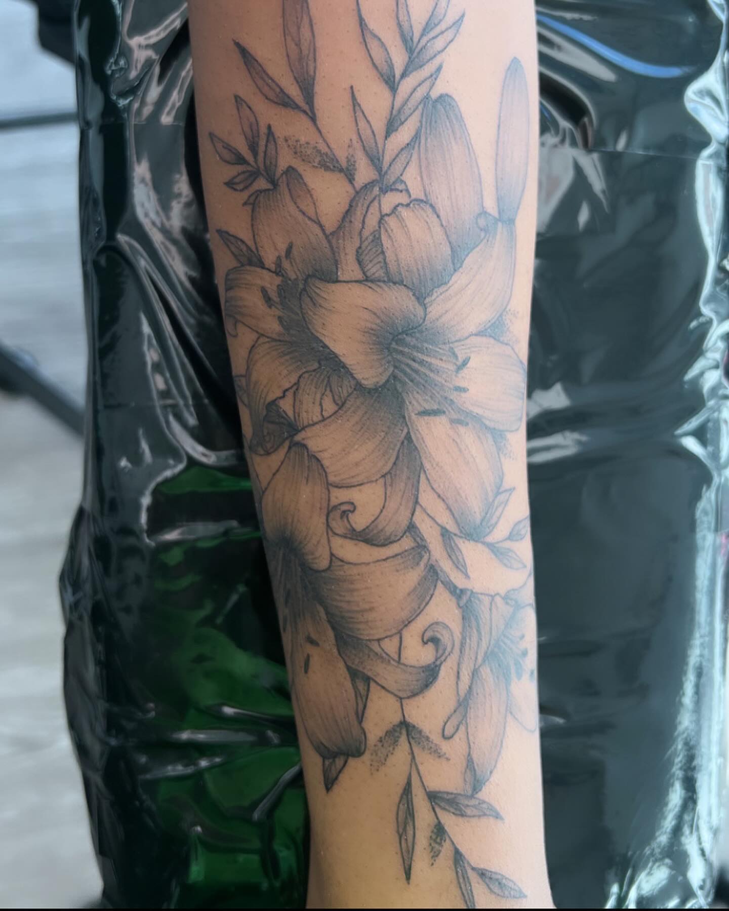 Lily flowers black and grey tattoo on the forearm by Syd Cheyenne