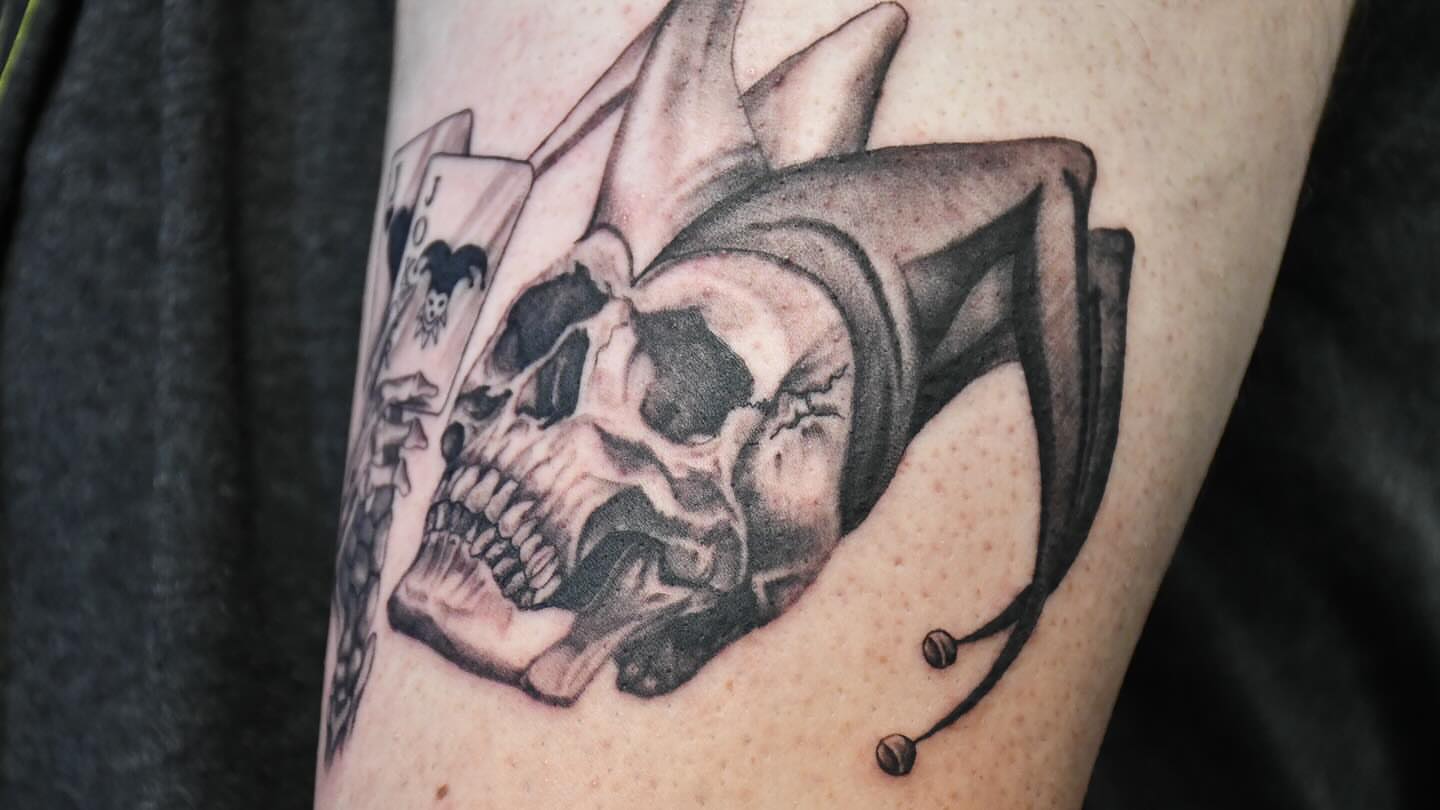 Skull and playing cards realism tattoo on the forearm by Jaiden Ducoff