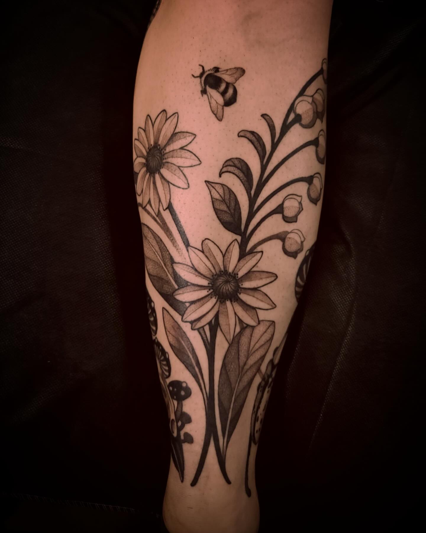 Flowers and bee black and grey tattoo on the forearm by Natasha Dickinson