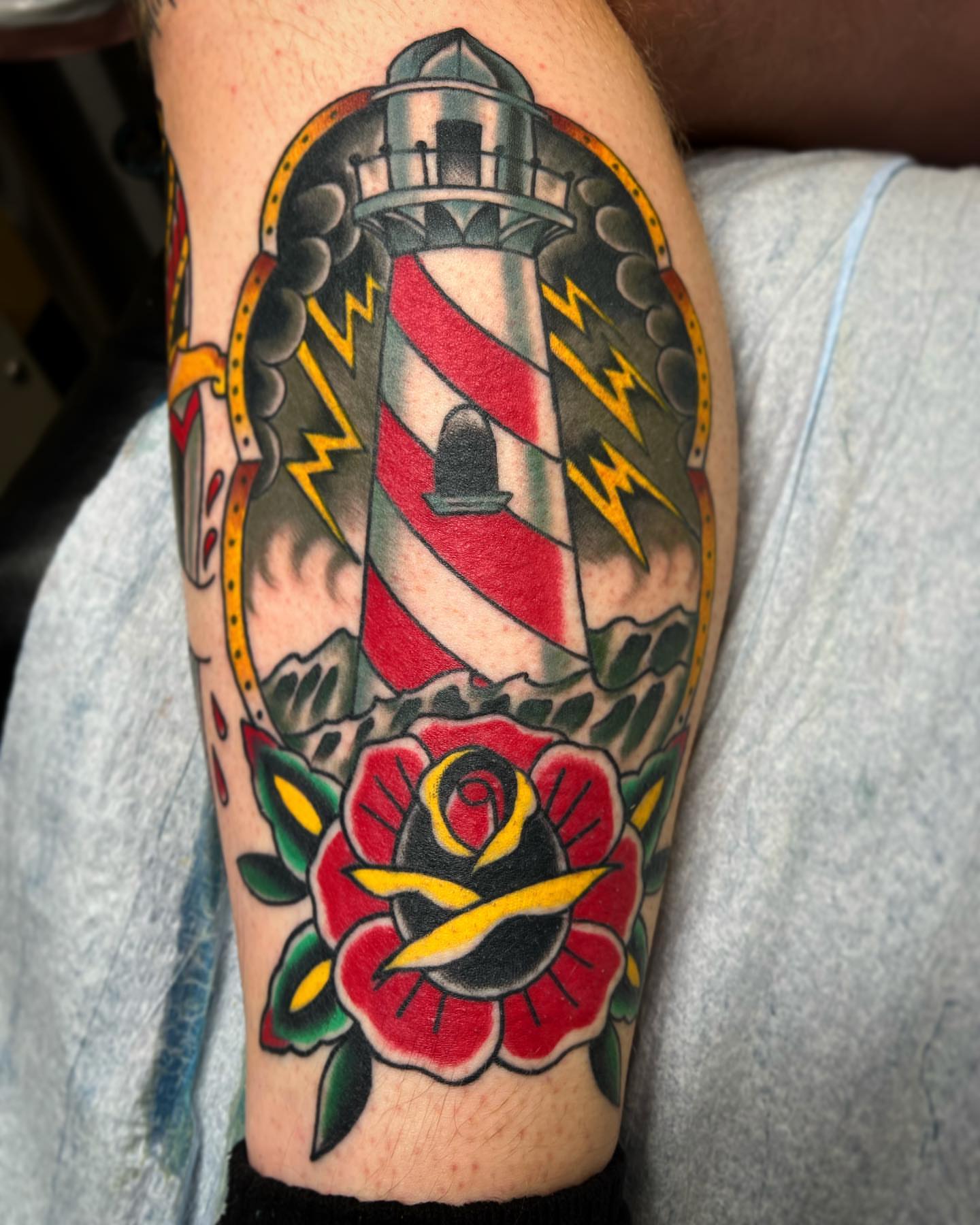 Lighthouse and rose American traditional tattoo on the forearm by Dustin Hysell