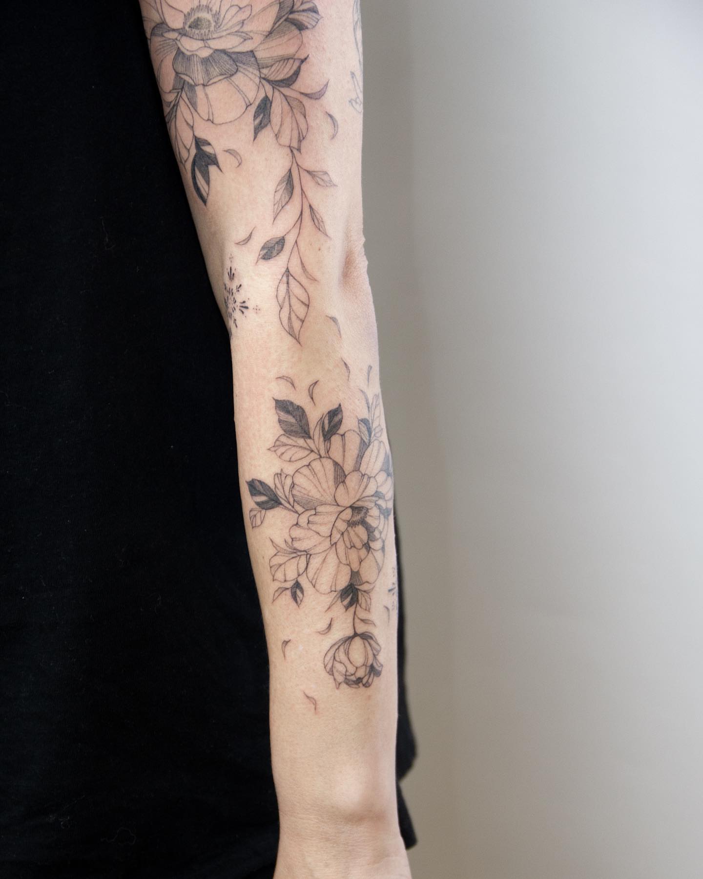 Floral arrangement black and grey tattoo on the forearm by Liv