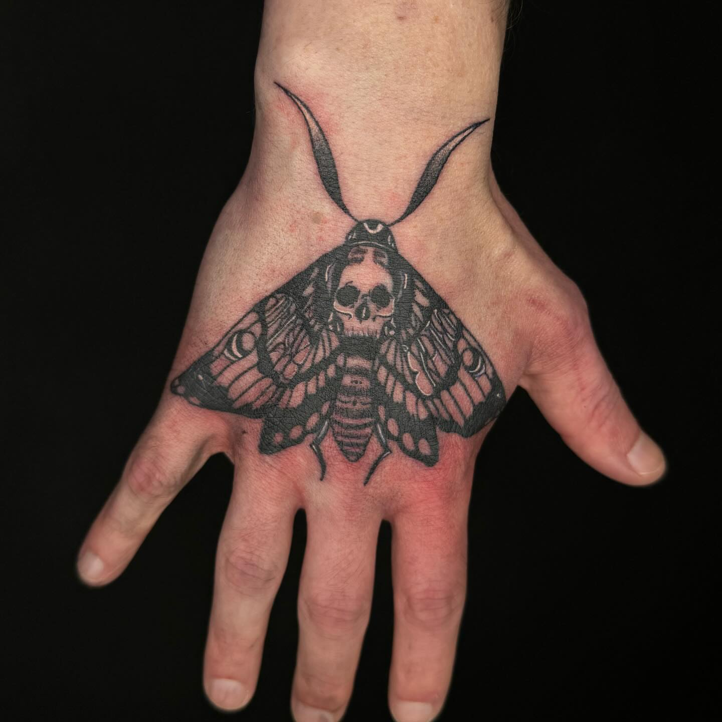 Moth with skull black and grey tattoo on the hand by @inkedbybanti