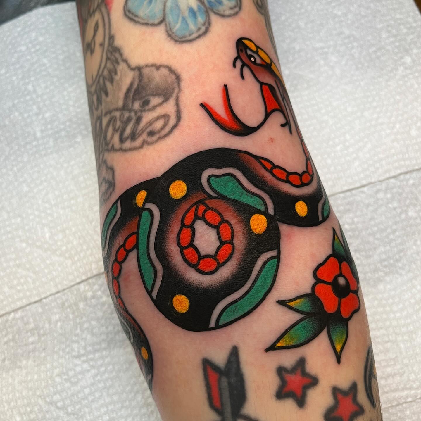 Snake and flower American traditional tattoo on the forearm by John Lemon