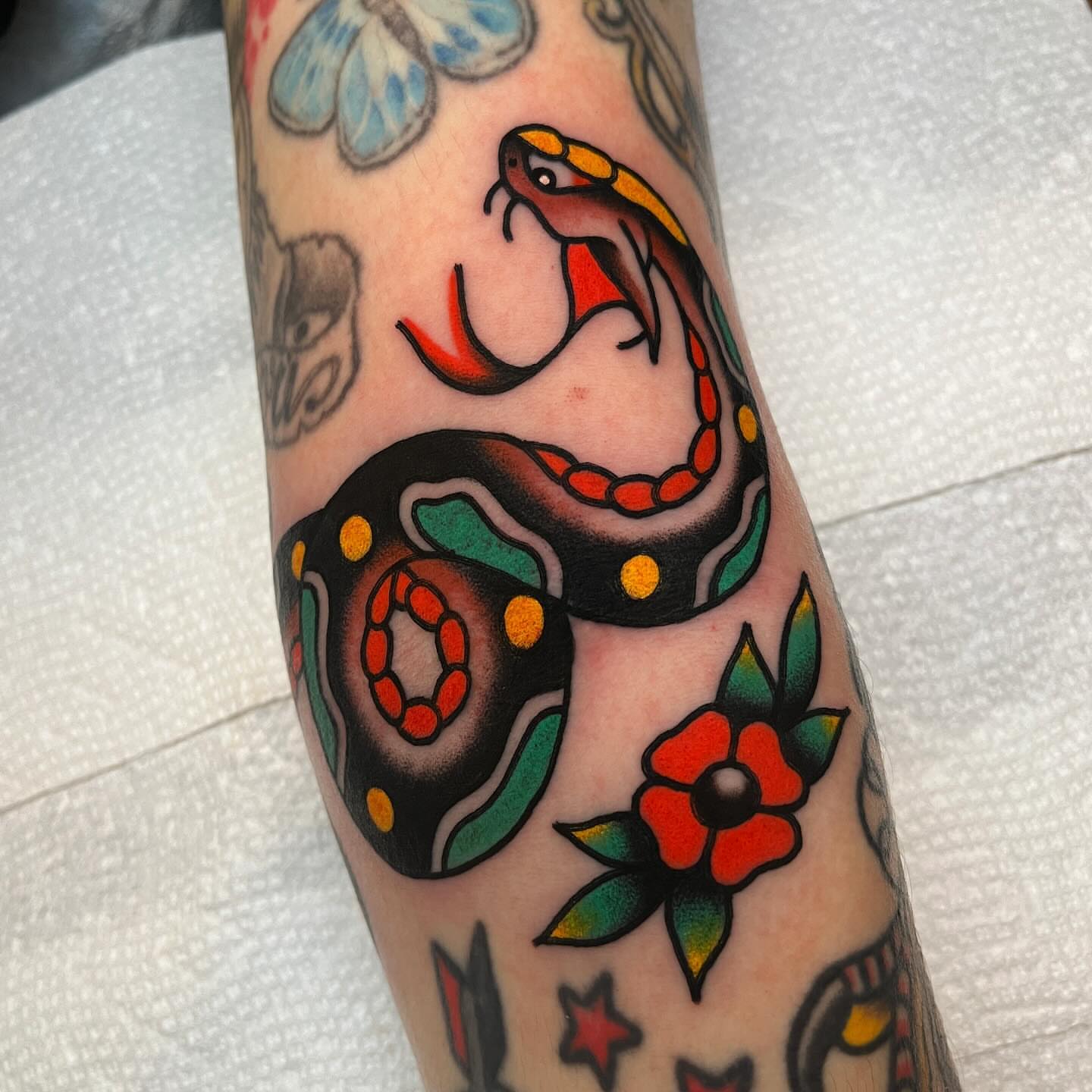 Snake and flower American traditional tattoo on the forearm by John Lemon
