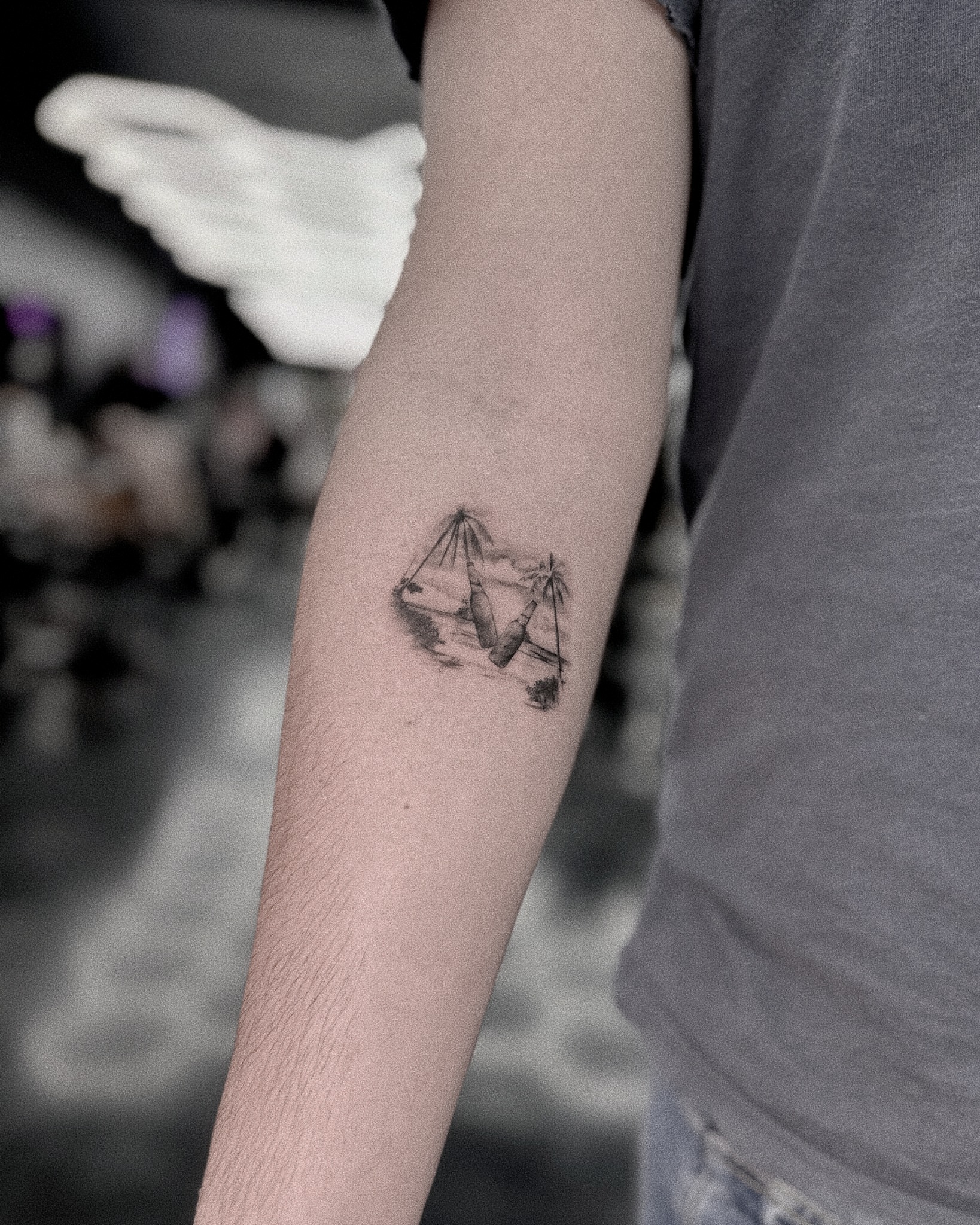 Swings and palm trees black and grey tattoo on the forearm by Ron Alvarez