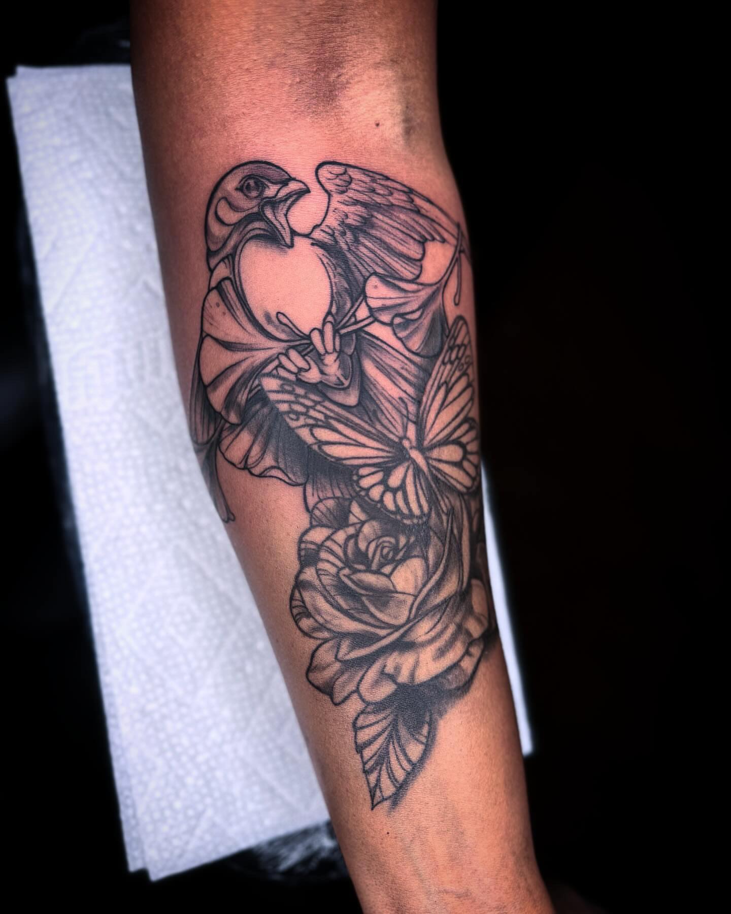 Bird and butterfly black and grey tattoo on the forearm by @inkhazmat