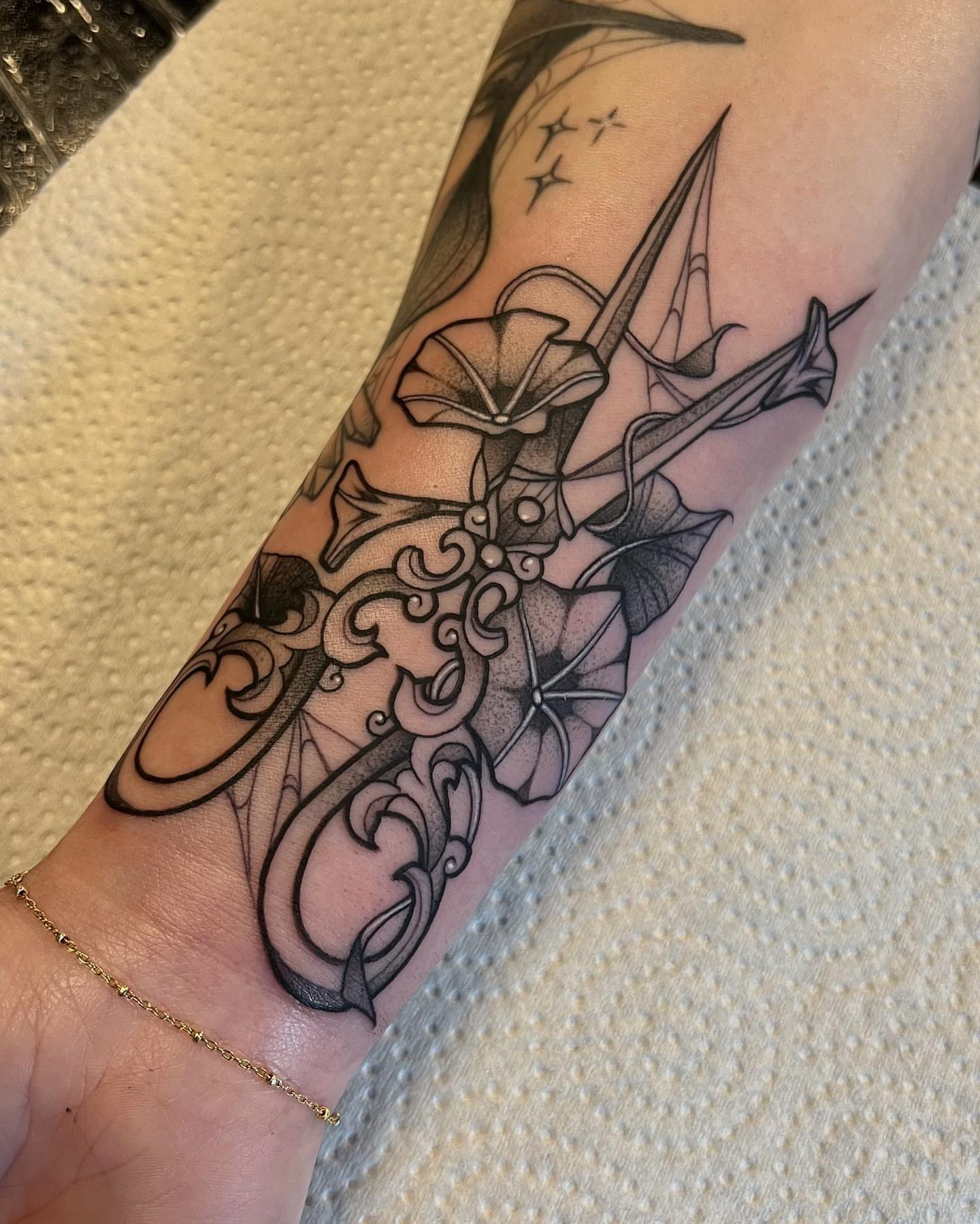 Sword and floral ornamental tattoo on the forearm by Bell Bolton