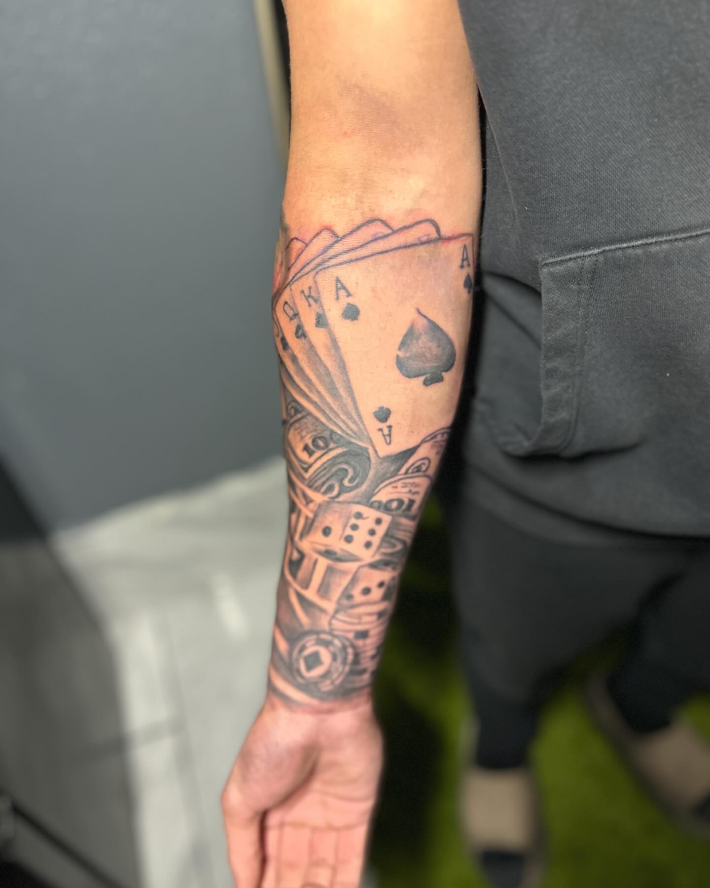 Playing cards and dice black and grey tattoo on the forearm by DC