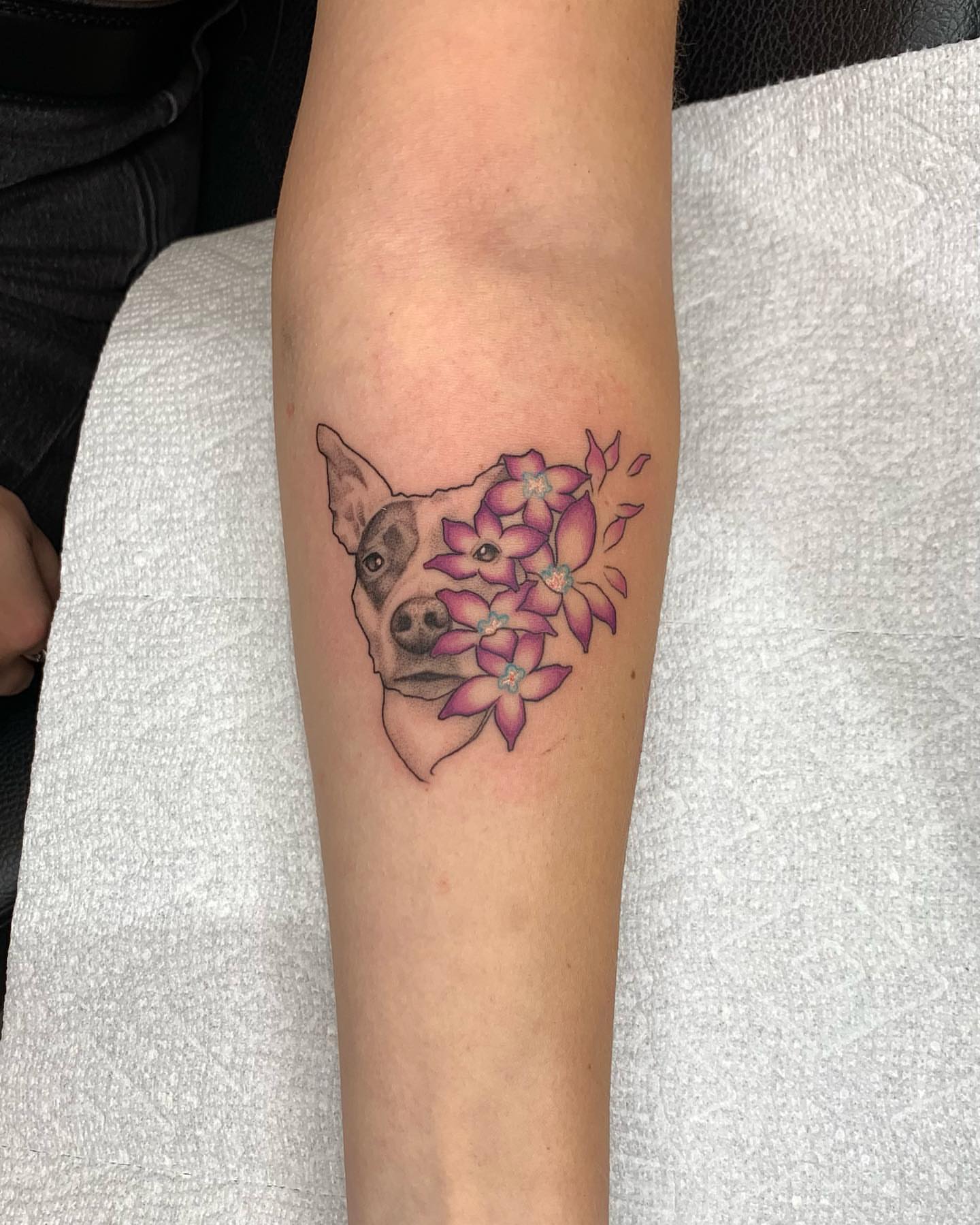 Dog with flowers realism tattoo on the forearm by Mike G.