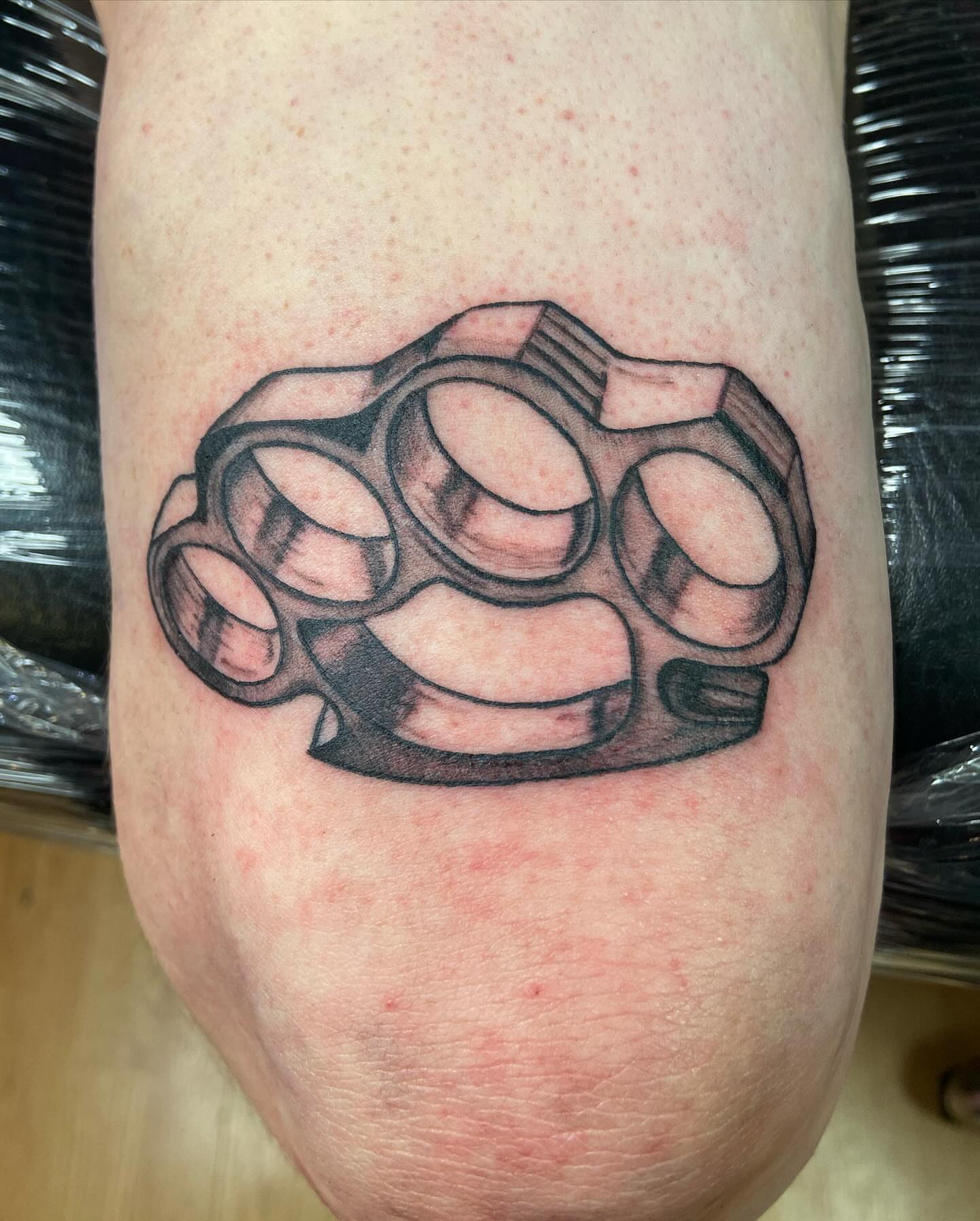 Brass knuckles black and grey tattoo on the forearm by Ride The Needle Tattoos, New Britain, Connecticut