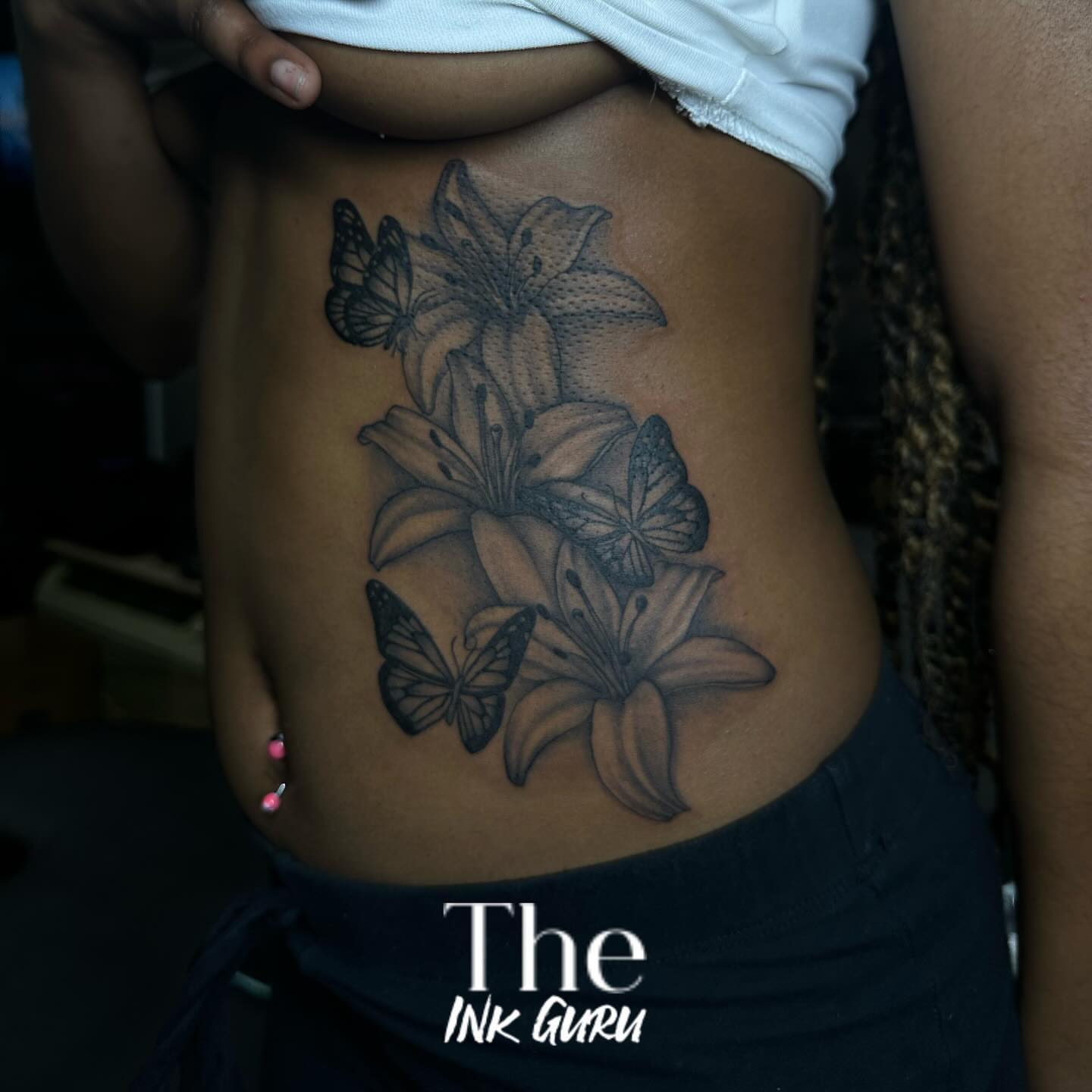 Lilies and butterflies black and grey tattoo on the ribs by The Ink Guru.