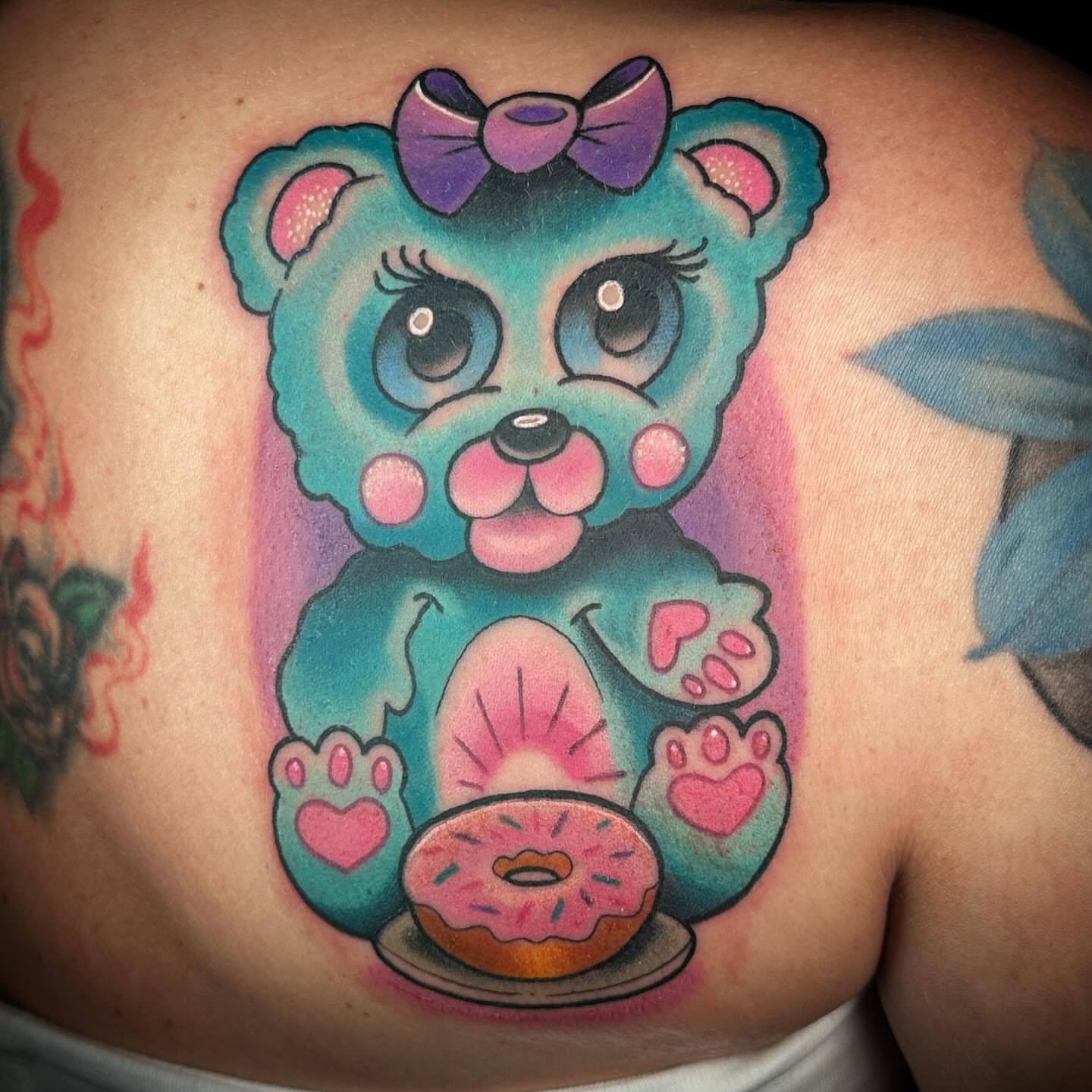 Teddy bear with donut new school tattoo on the back by B.G. Germershausen
