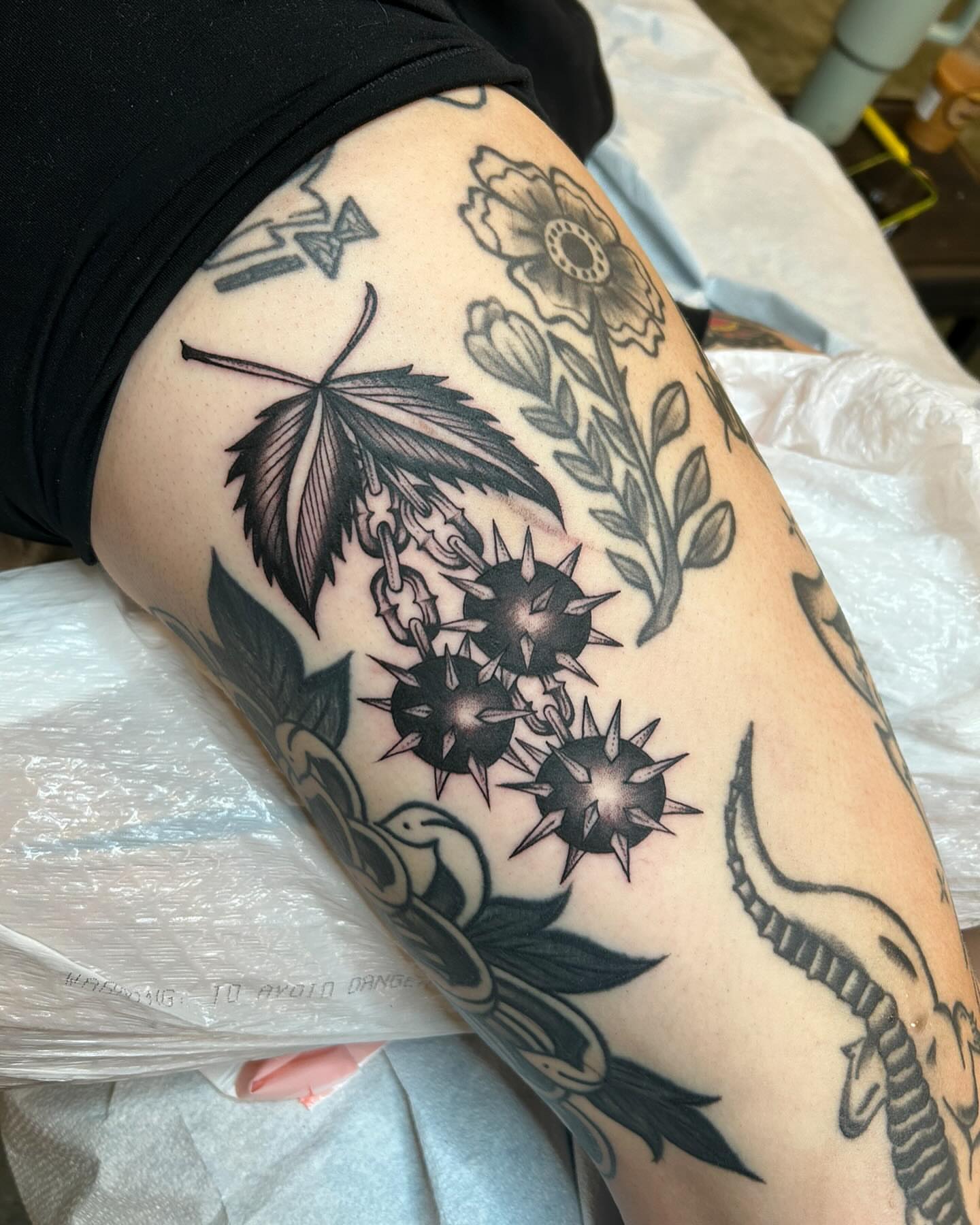 Marijuana leaf and sunburst black and grey tattoo on the thigh by Sam Perry, Denver, Colorado
