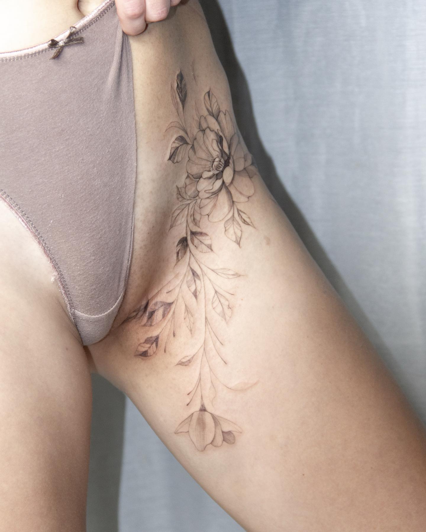 Floral arrangement black and grey tattoo on the thigh by Liv
