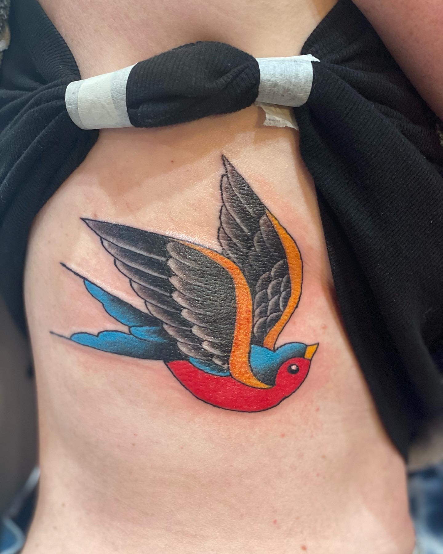 Swallow American traditional tattoo on the ribs by Christopher Sanders