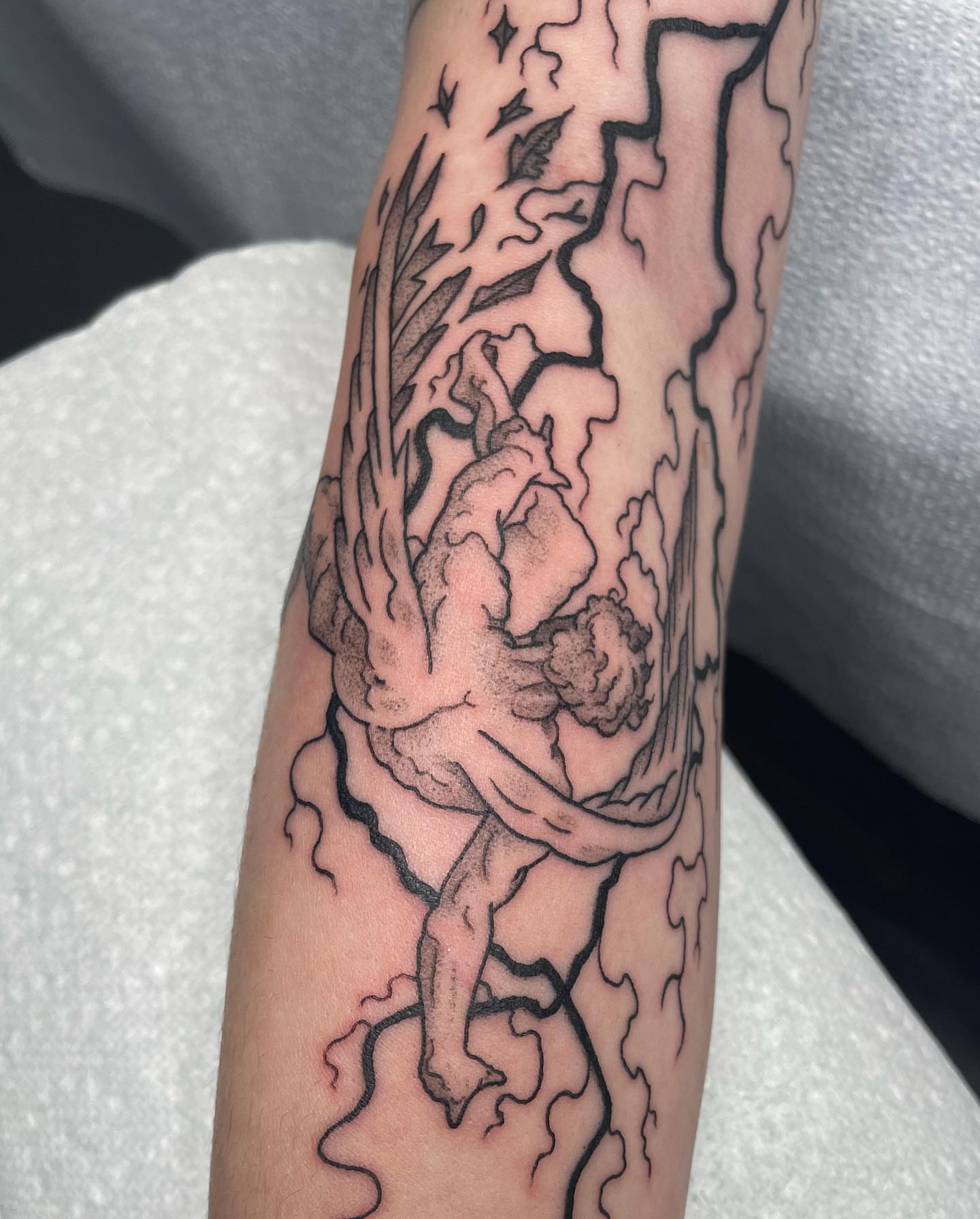 Angelic figure black and grey tattoo on the forearm by Sylvie