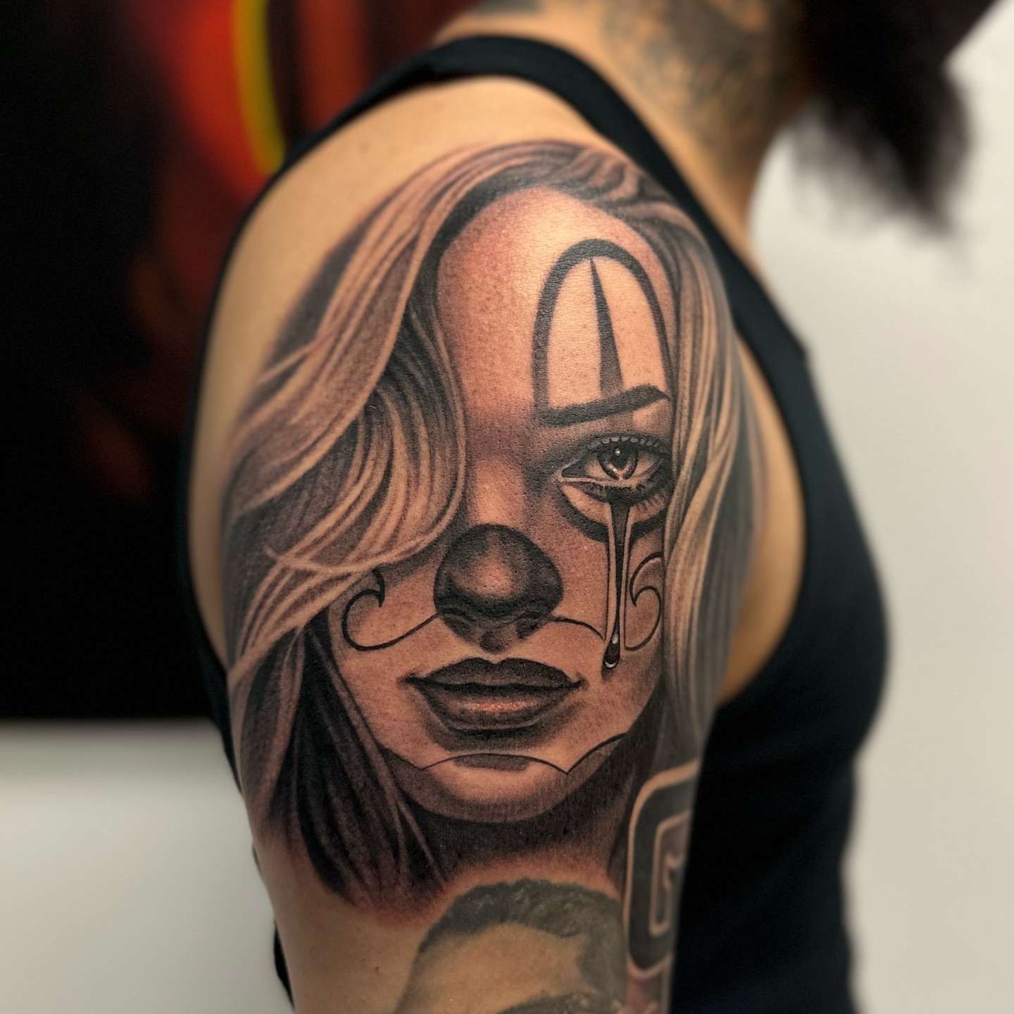 Clown face realism tattoo on the shoulder by Junior Nunez