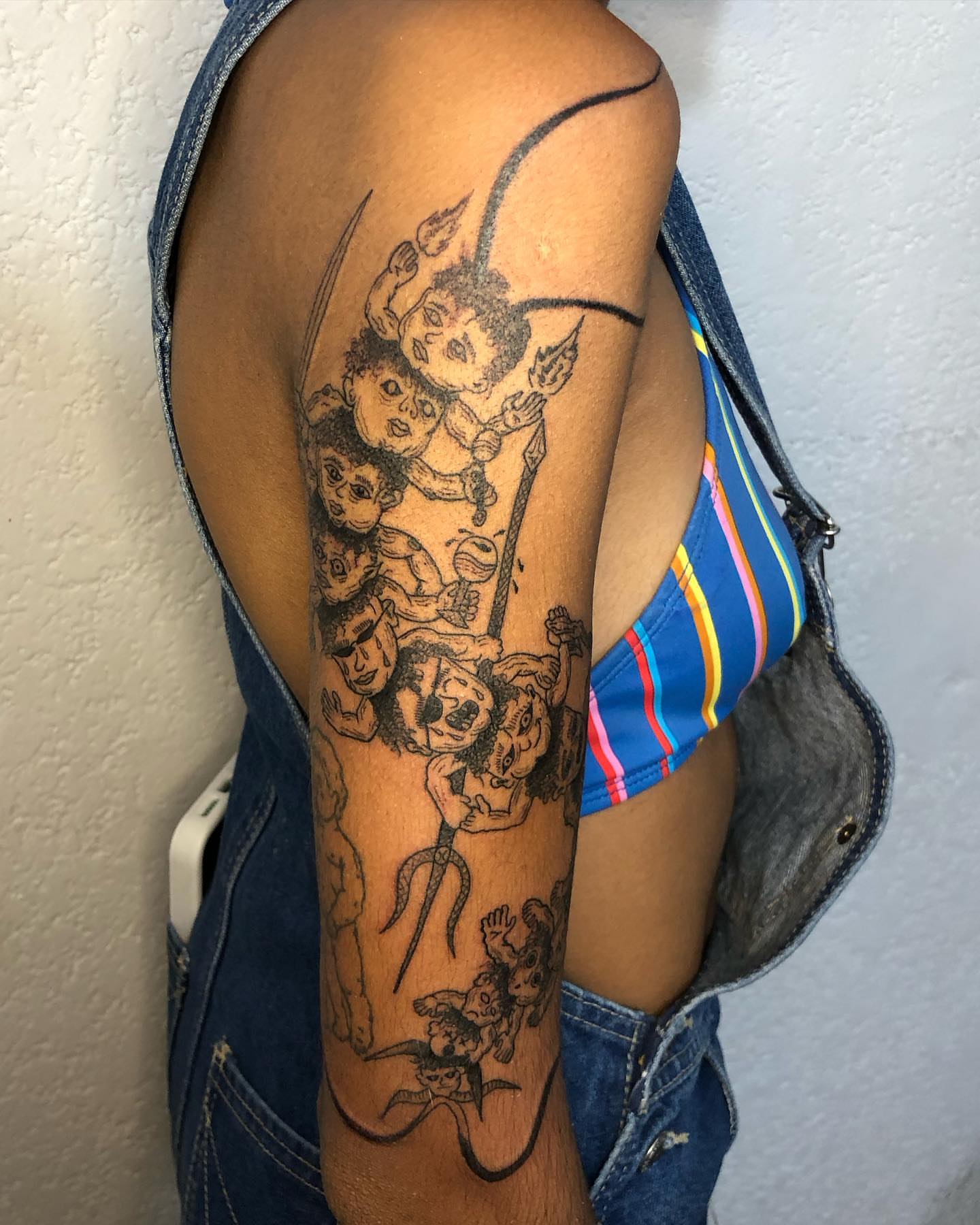 Group of figures black and grey tattoo on the upper arm by Barro