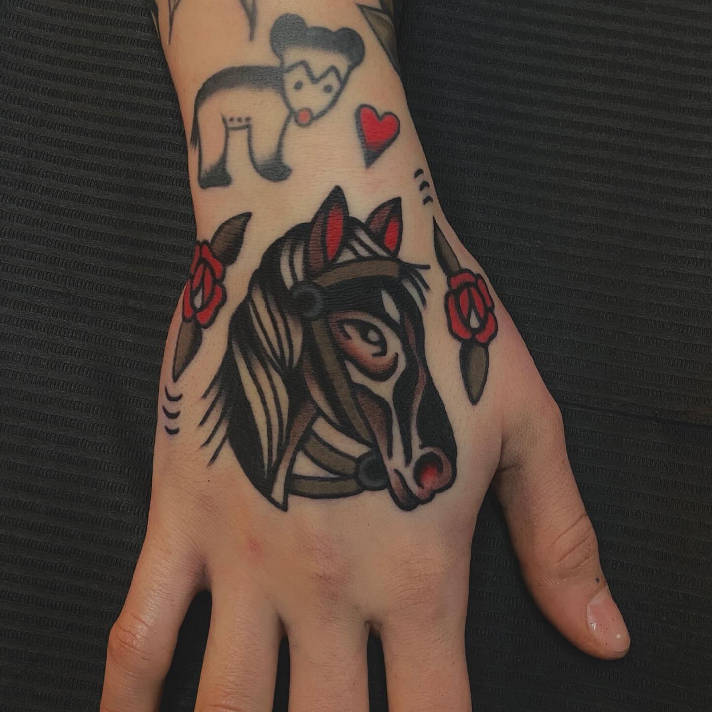 Horse with roses American traditional tattoo on the hand by Erin Chambers