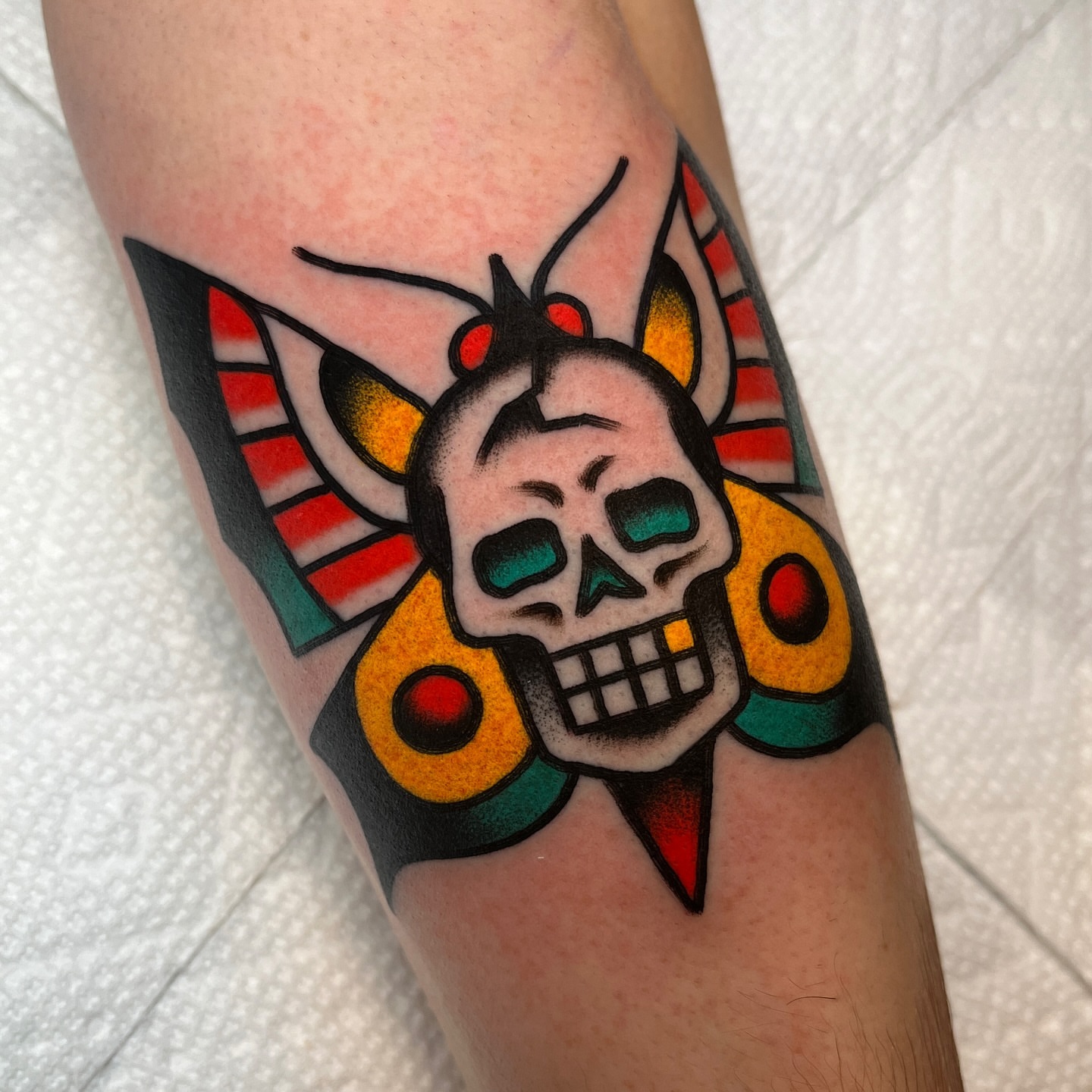 Skull with wings American traditional tattoo on the forearm by John Lemon