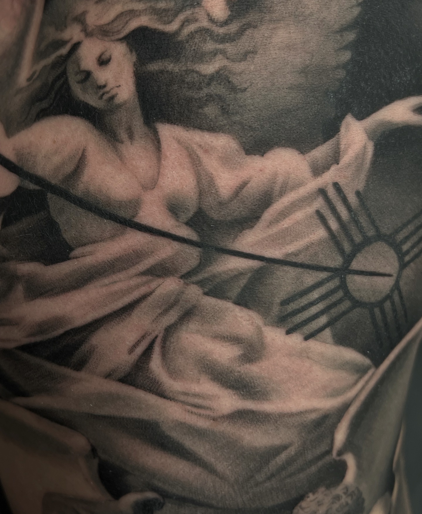 Woman with bow black and grey tattoo on the upper arm by Madison Ast Tattoo