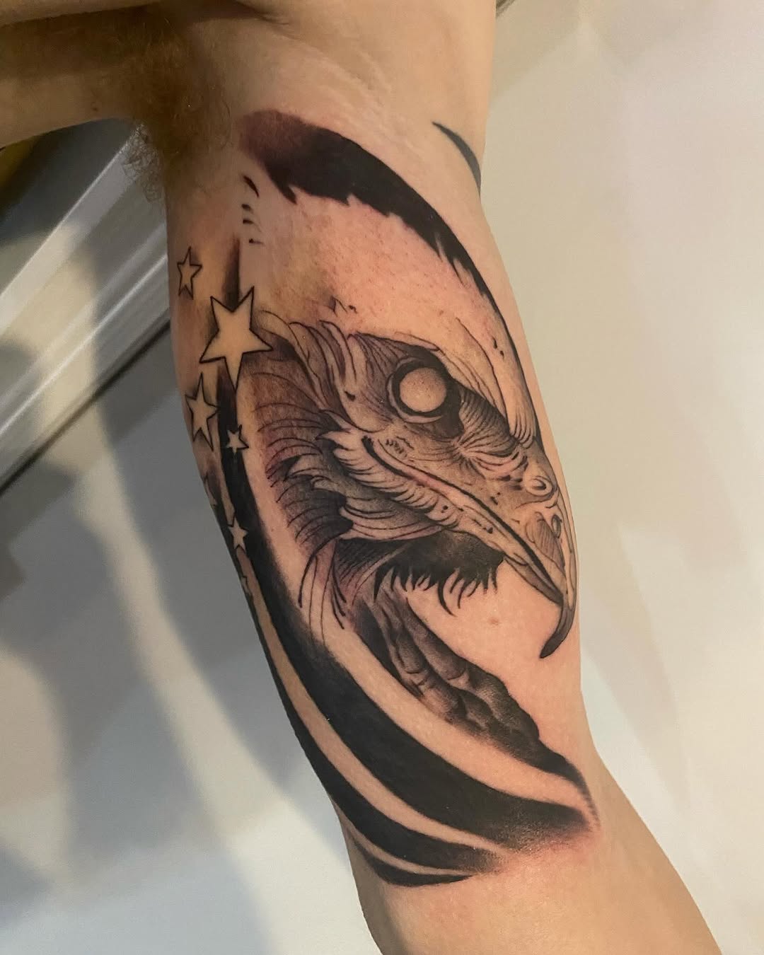 Eagle head with stars realism tattoo on the forearm by Cody Wolfe