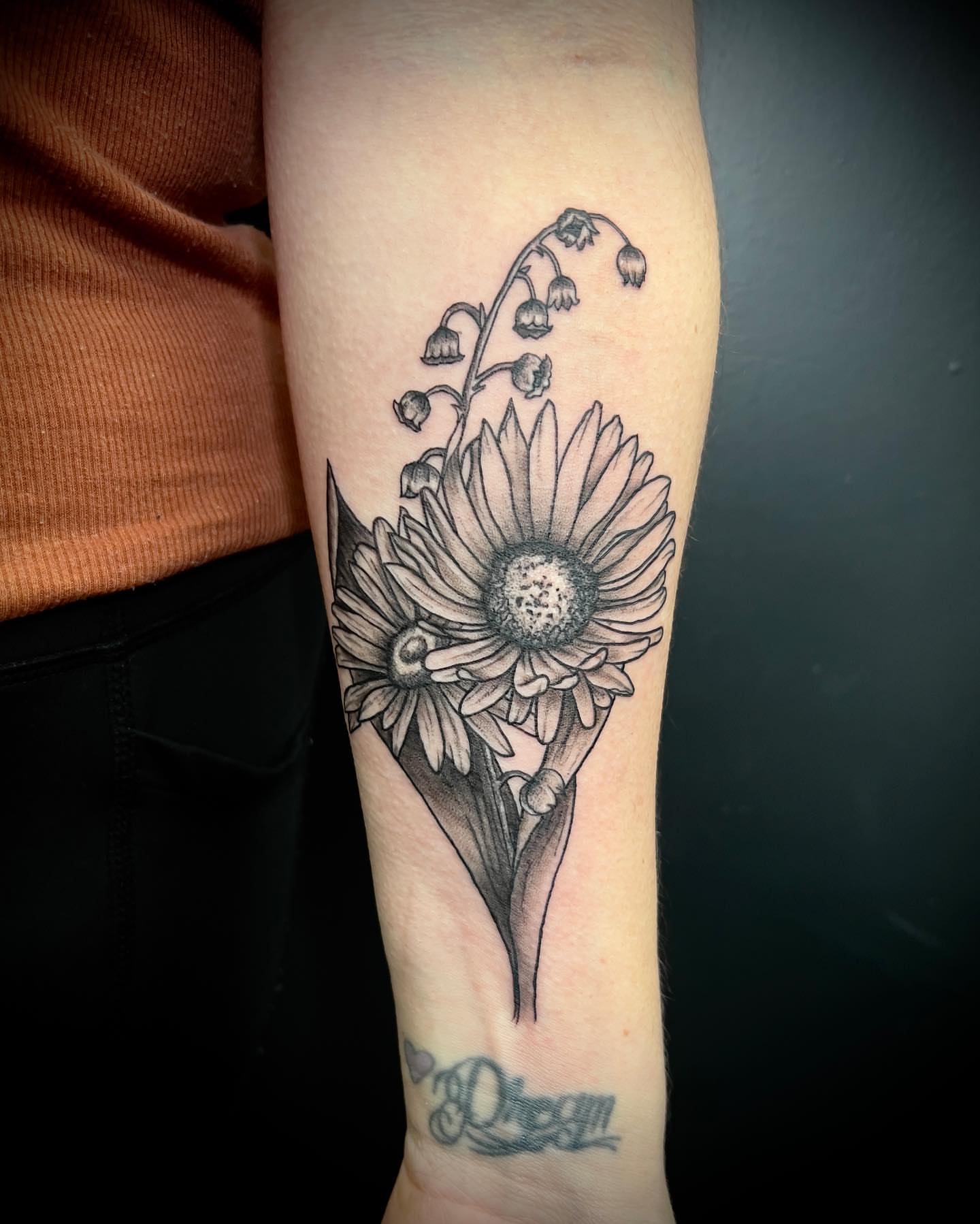 Daisy and lilies of the valley black and grey tattoo on the forearm by Tattoos by Katherina, Willoughby, Ohio