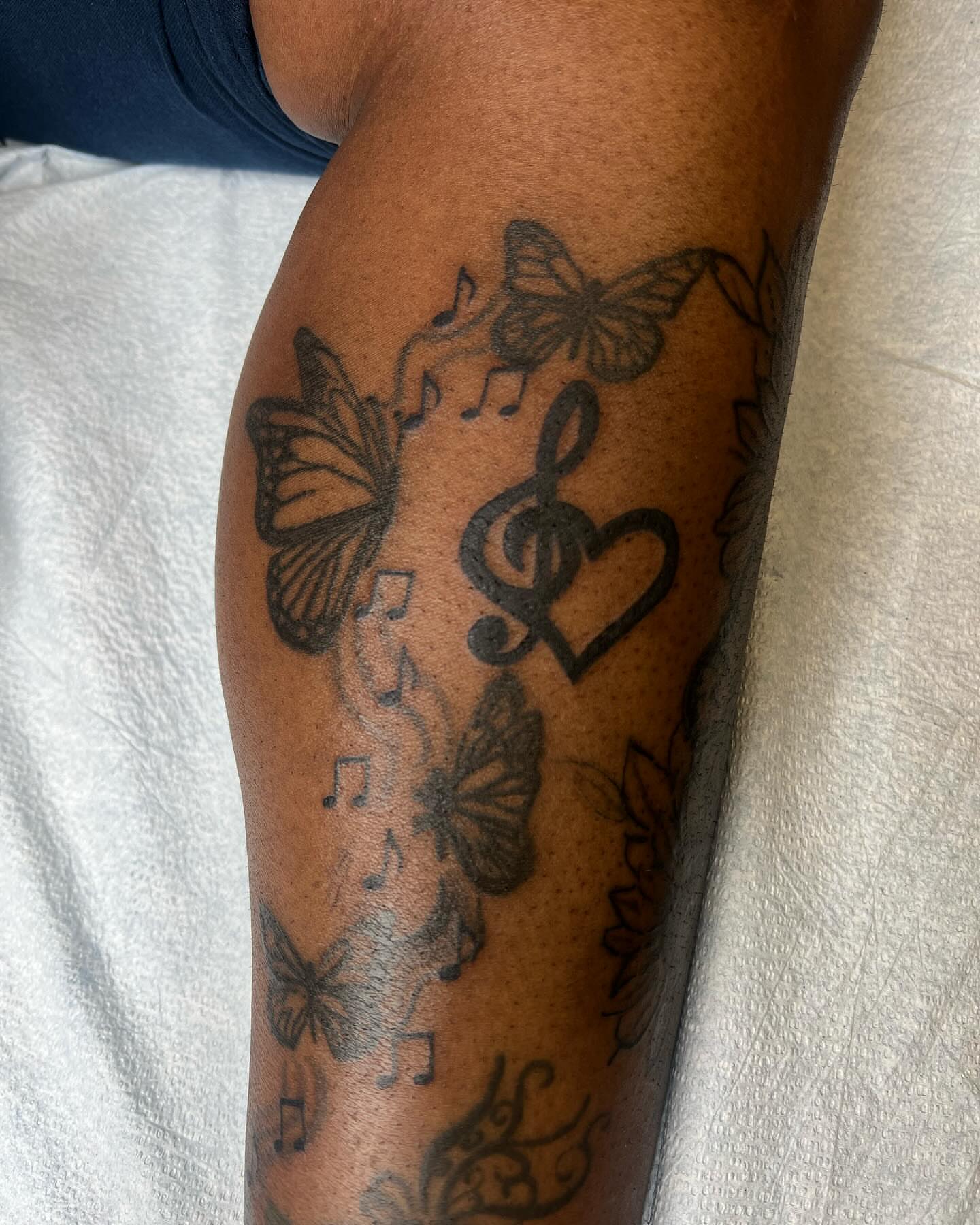 Music notes and butterflies black and grey tattoo on the forearm by Kai