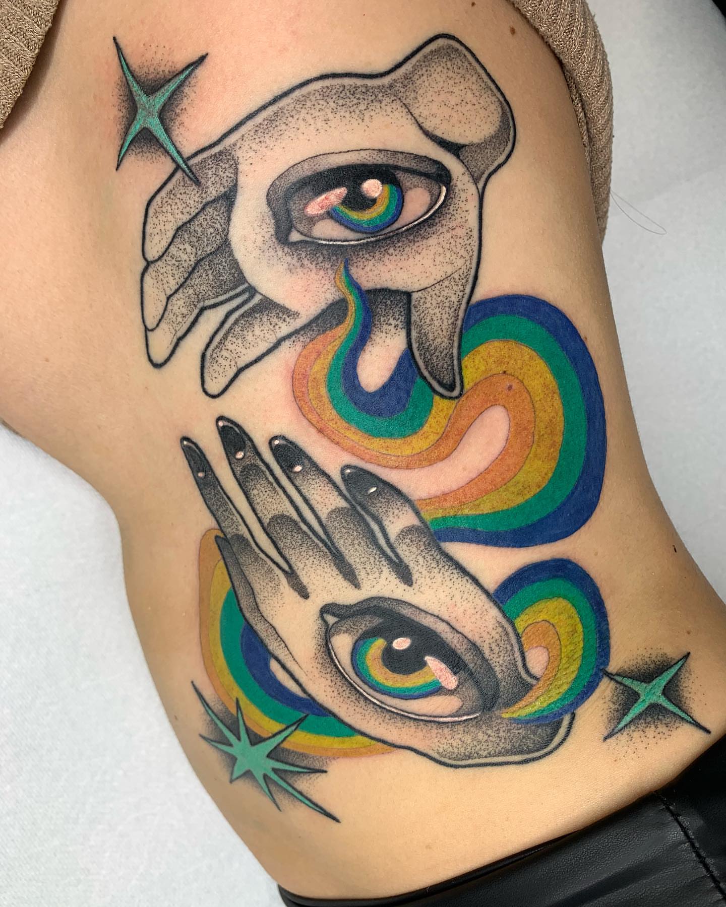 Eyes and rainbow dotwork tattoo on the shoulder by Carly Zehring