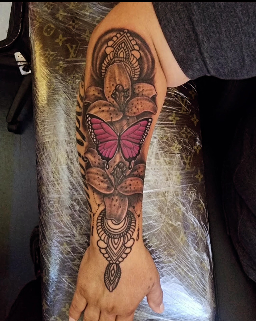Lily and butterfly dotwork tattoo on the forearm by Germaine Sherman
