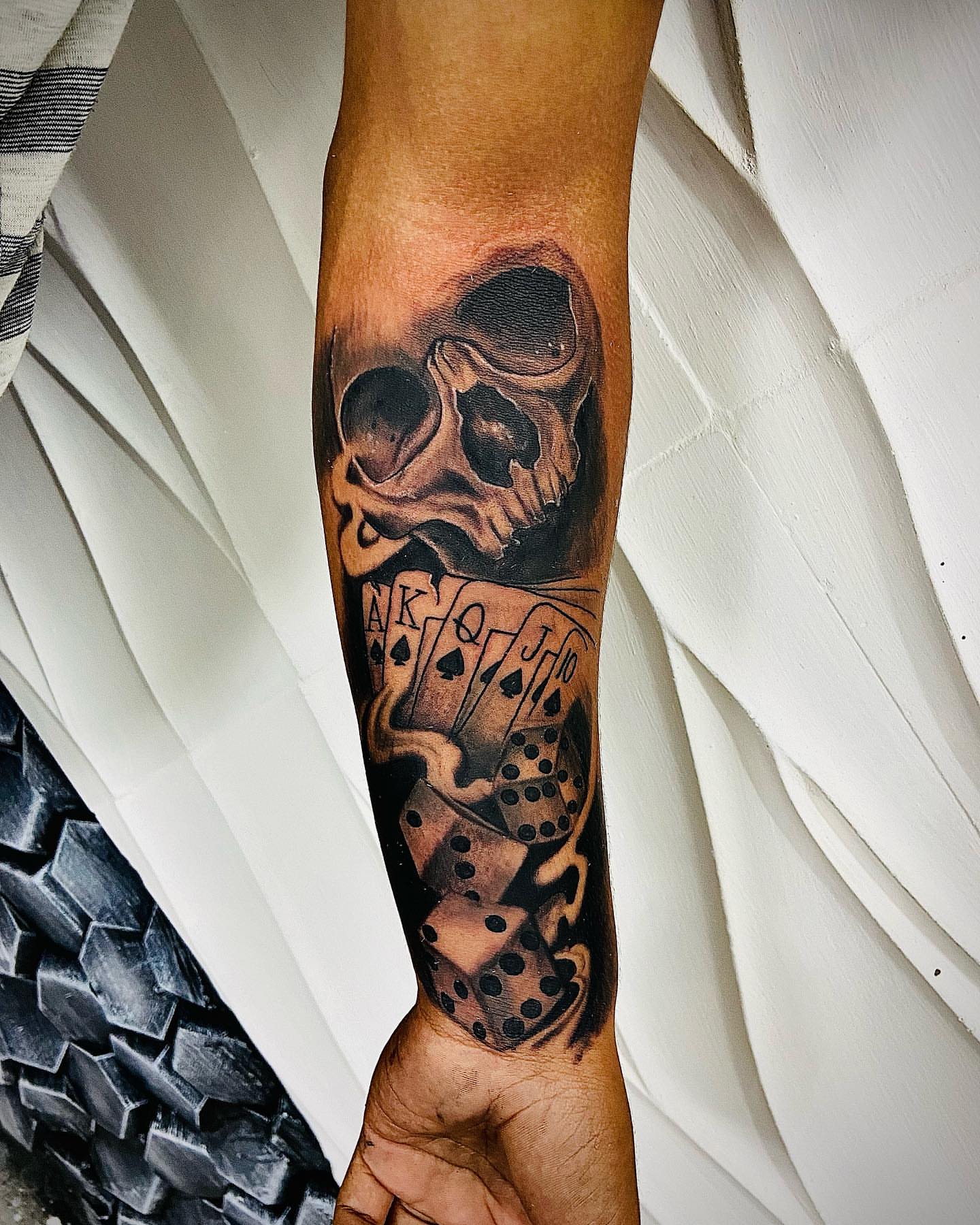 Skull and playing cards realism tattoo on the forearm by Aldocasales@tatto