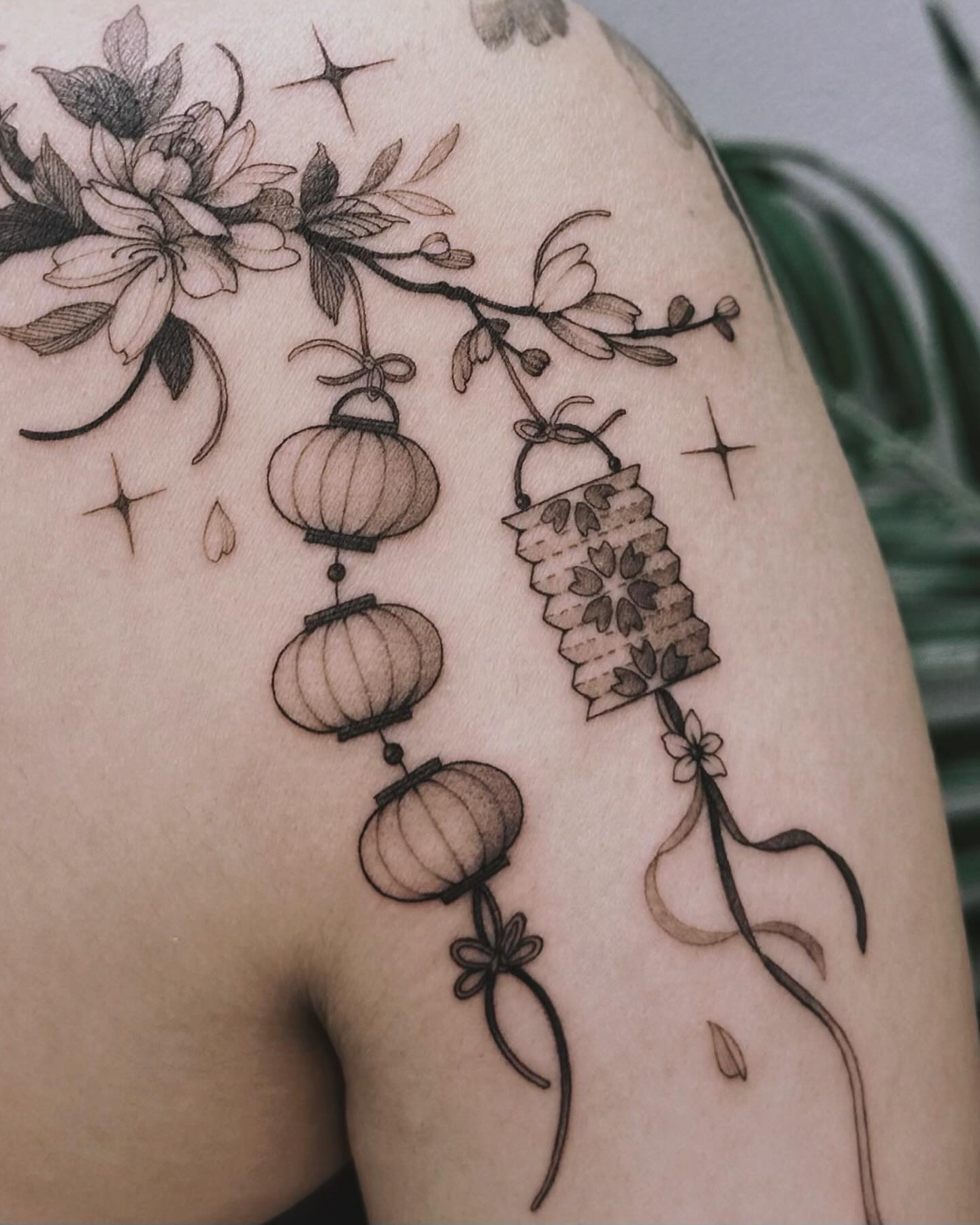 Lanterns and flowers black and grey tattoo on the shoulder by Angel