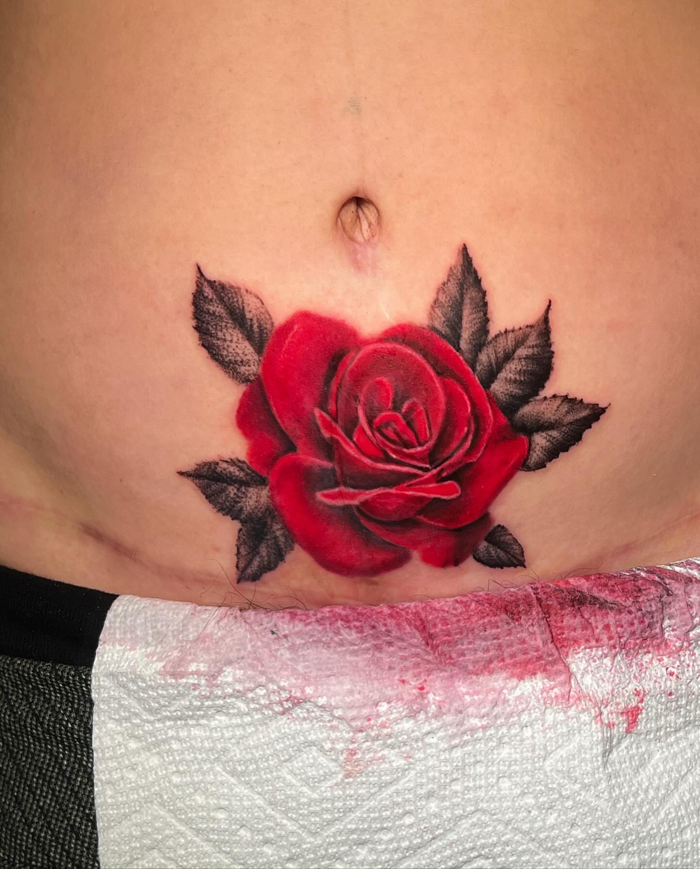 Red rose realism tattoo on the torso by Ryan
