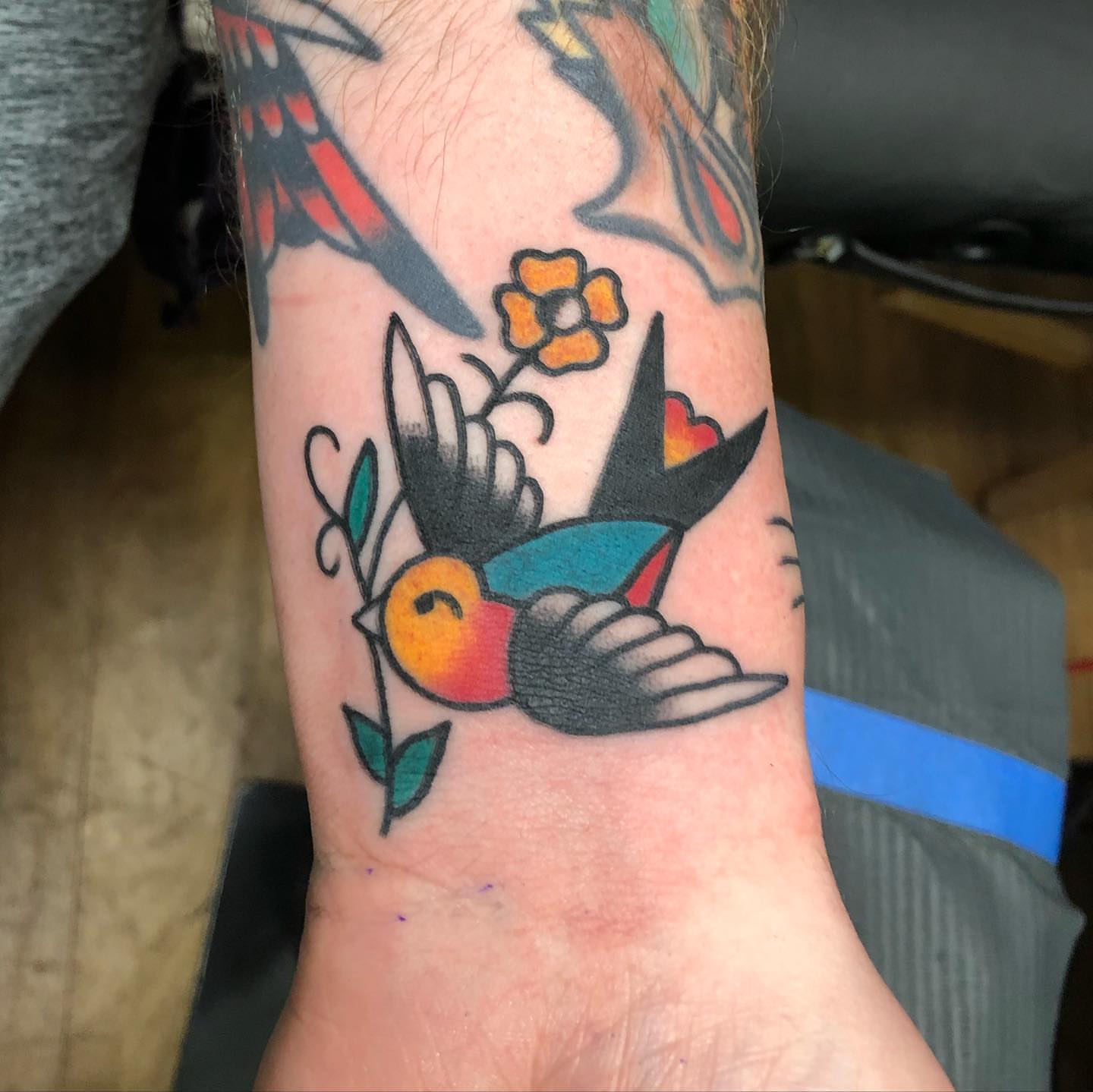 Bird and flower American traditional tattoo on the forearm by Brent G